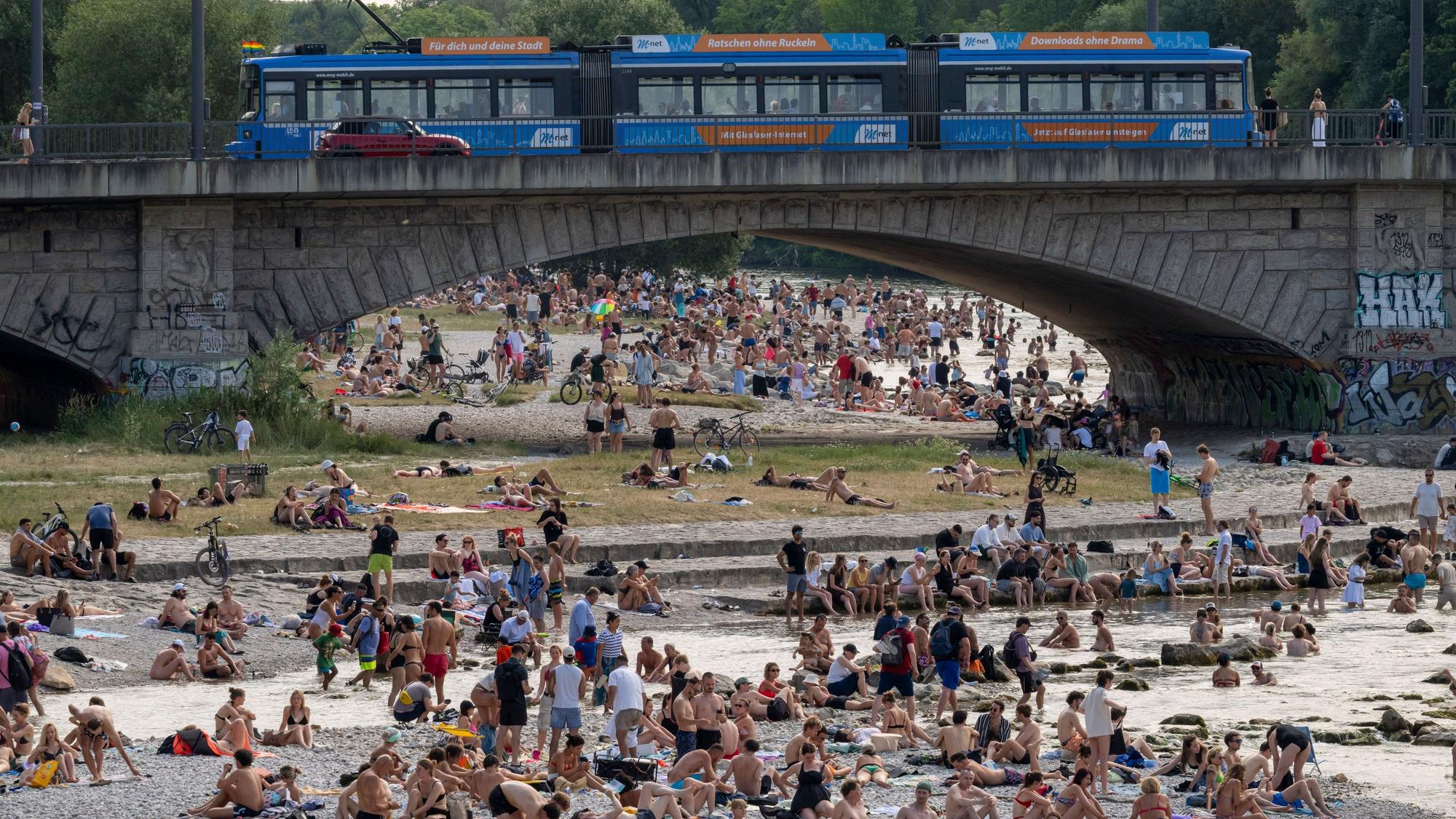 Badende genießen die Abkühlung im Wasser der Isar im Herzen der bayerischen Landeshauptstadt.