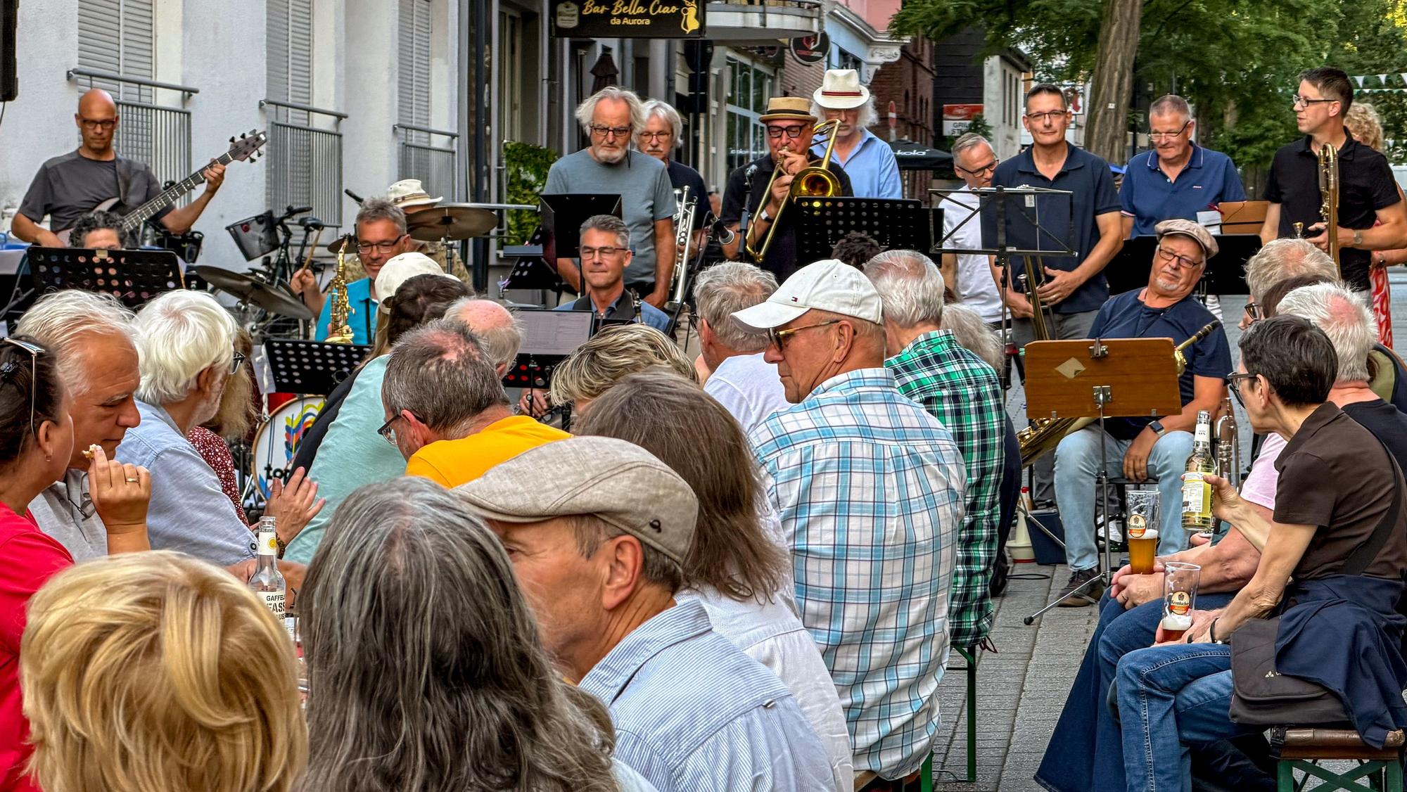 Die Leverkusen Big Band eröffnet unter ihrem neuen Namen vor dem Topos die Sommerferien musikalisch und lockt zahlreiche Besucherinnen und Besucher auf die gesperrte Hauptstraße.