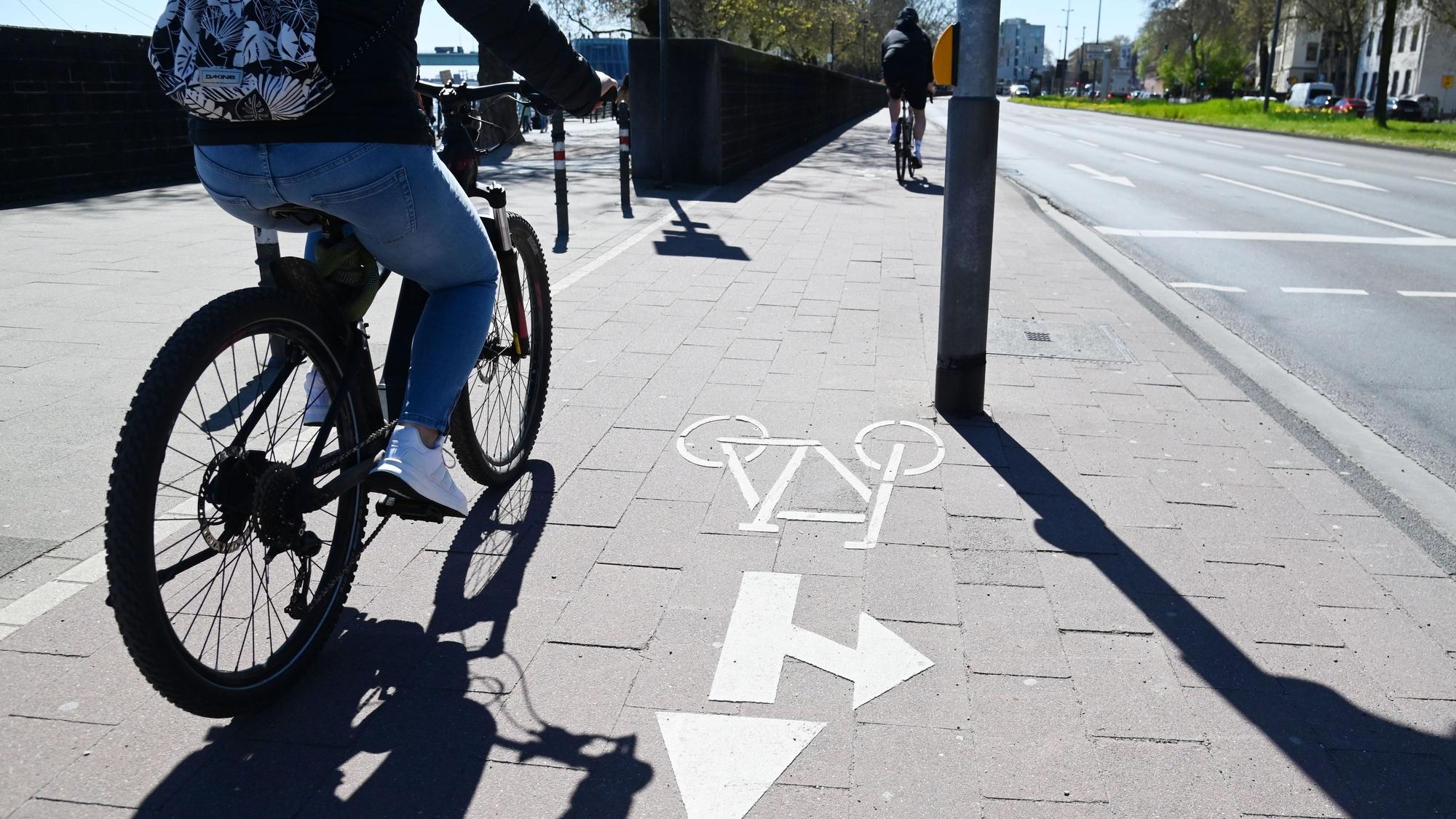 Ein Radfahrer fährt am Rheinufer in der Kölner Altstadt entlang. (Archivbild)