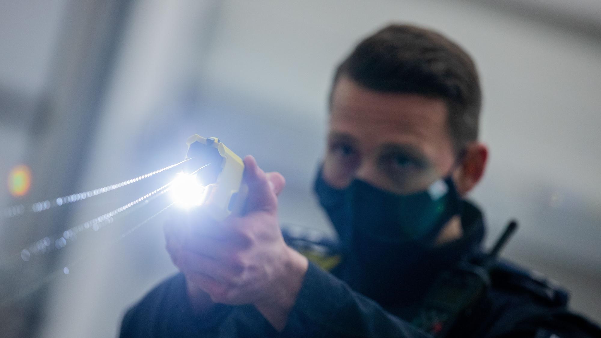 Ein Polizeibeamter demonstriert einen Schuss mit einem Distanzelektroimpulsgerät. Das Gerät sendet nach Abschuss zweier Elektroden Stromimpulse ab.