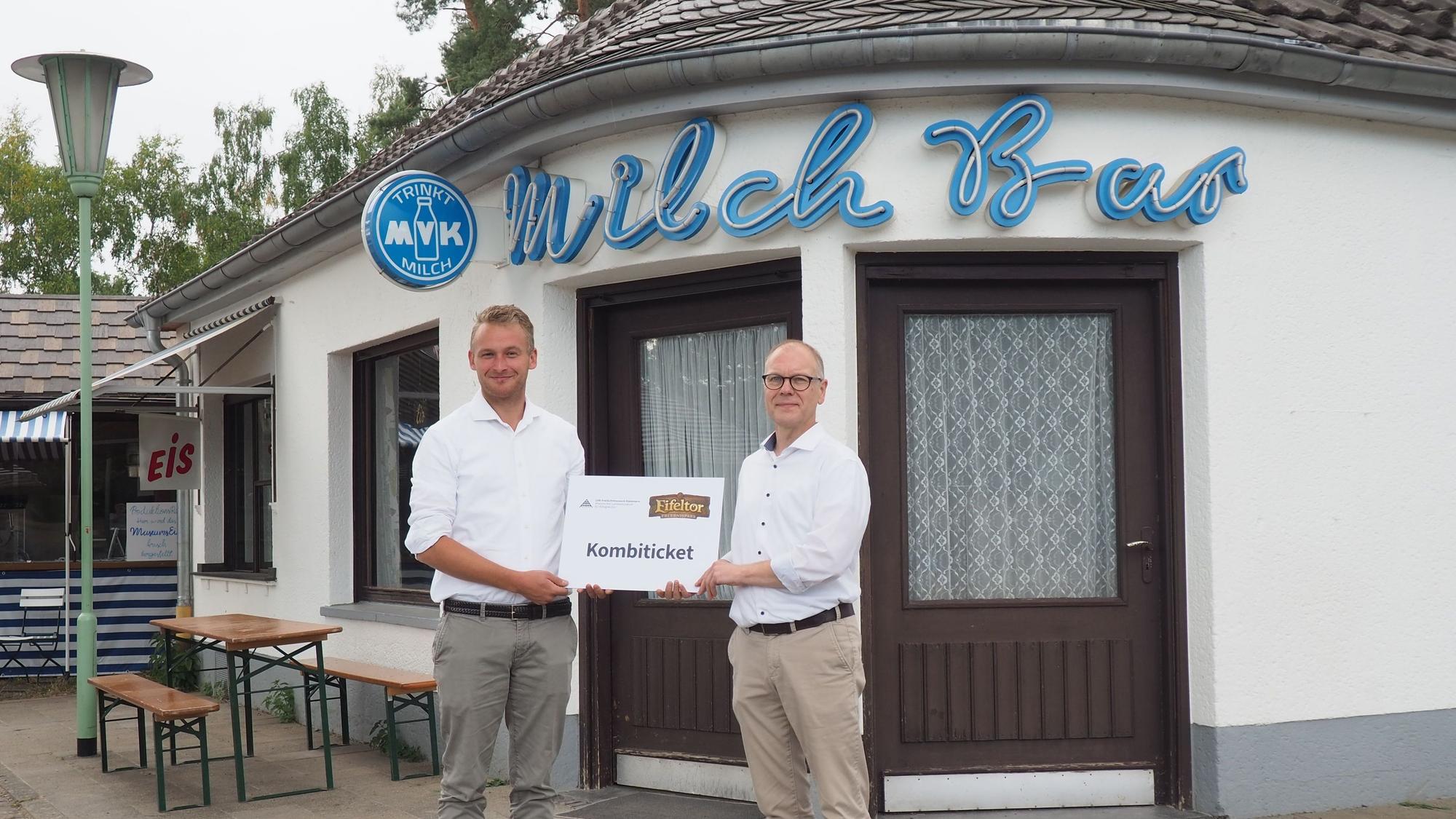Roland Barth (l.) und Dr. Carsten Vorwig stehen im Museum vor der Milchbar und halten gemeinsam ein übergroßes Kombiticket.