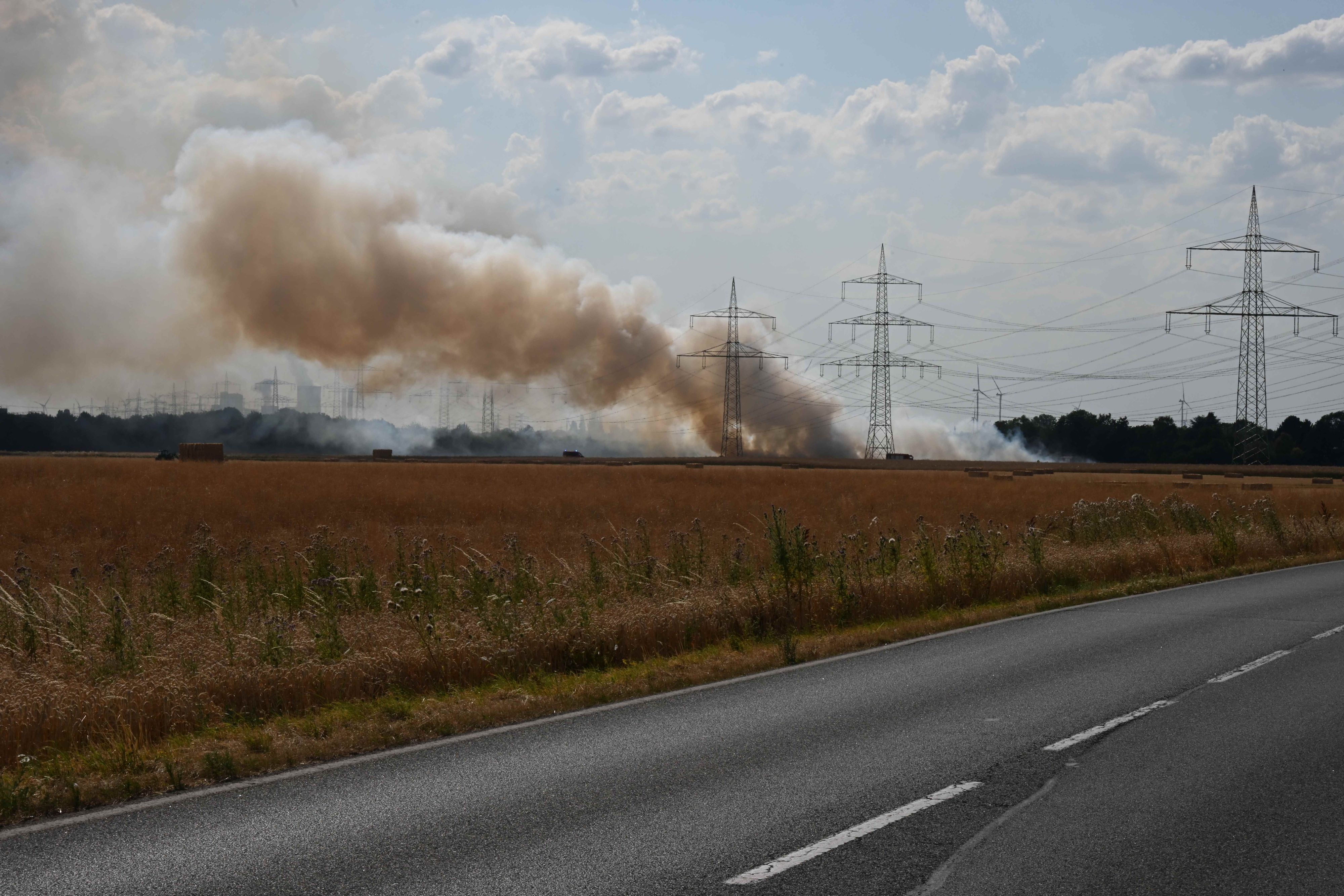 Ein Feuerwehrfahrzeug in der Nähe eines brennenden Feldes.