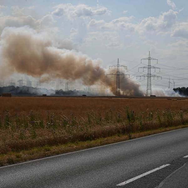 Ein Feuerwehrfahrzeug in der Nähe eines brennenden Feldes.