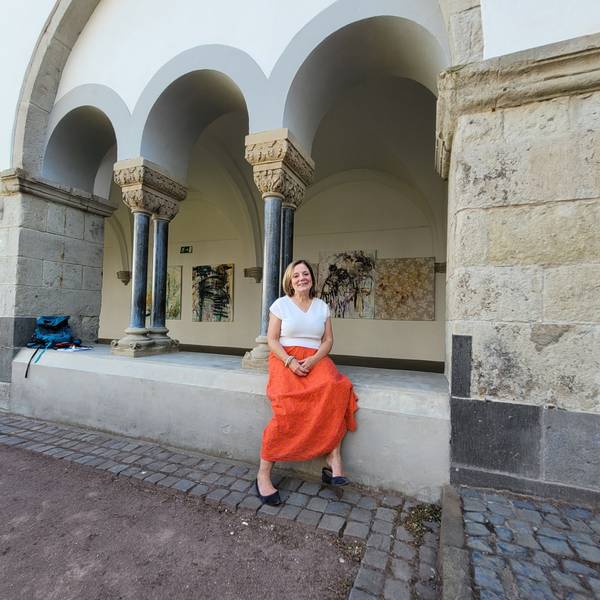 Eine Frau sitzt in einem Kreuzgang.