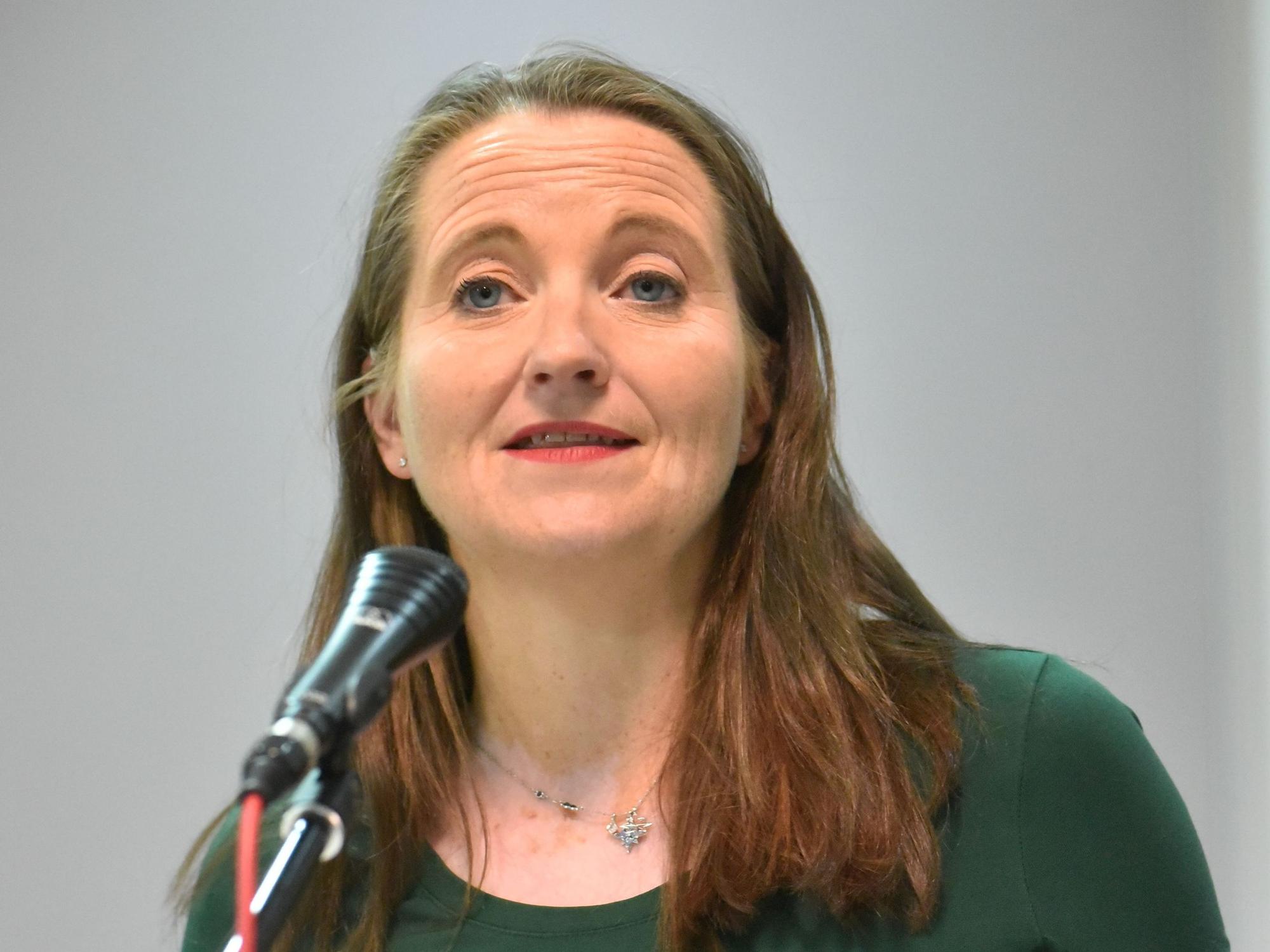 Auf dem Bild ist das Portrait einer Frau zu sehen, sie trägt ein grünes T-Shirt.