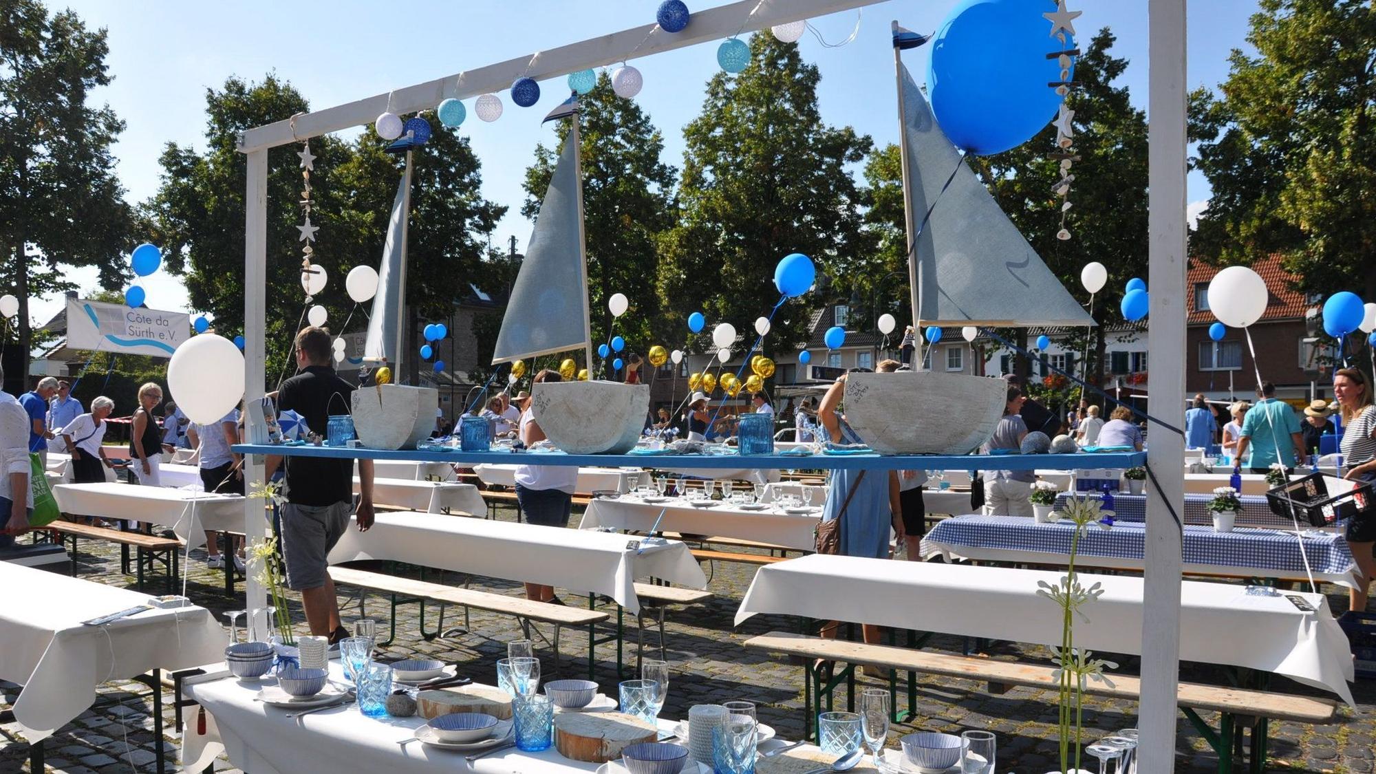 In Blau-Weiß eingedeckte Tische stehen auf einem Marktplatz.