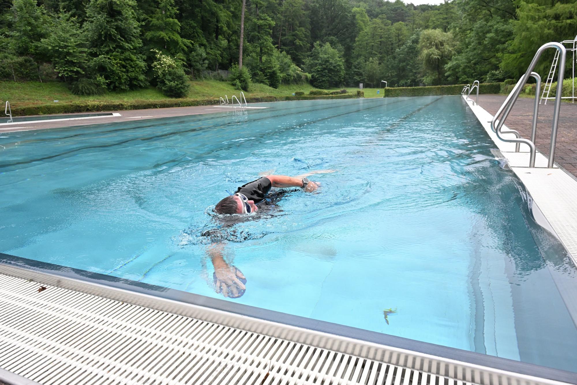 Ein Mann mit Schwimmbrille und kurzärmligem Neoprenanzug krault durch ein Schwimmbecken.