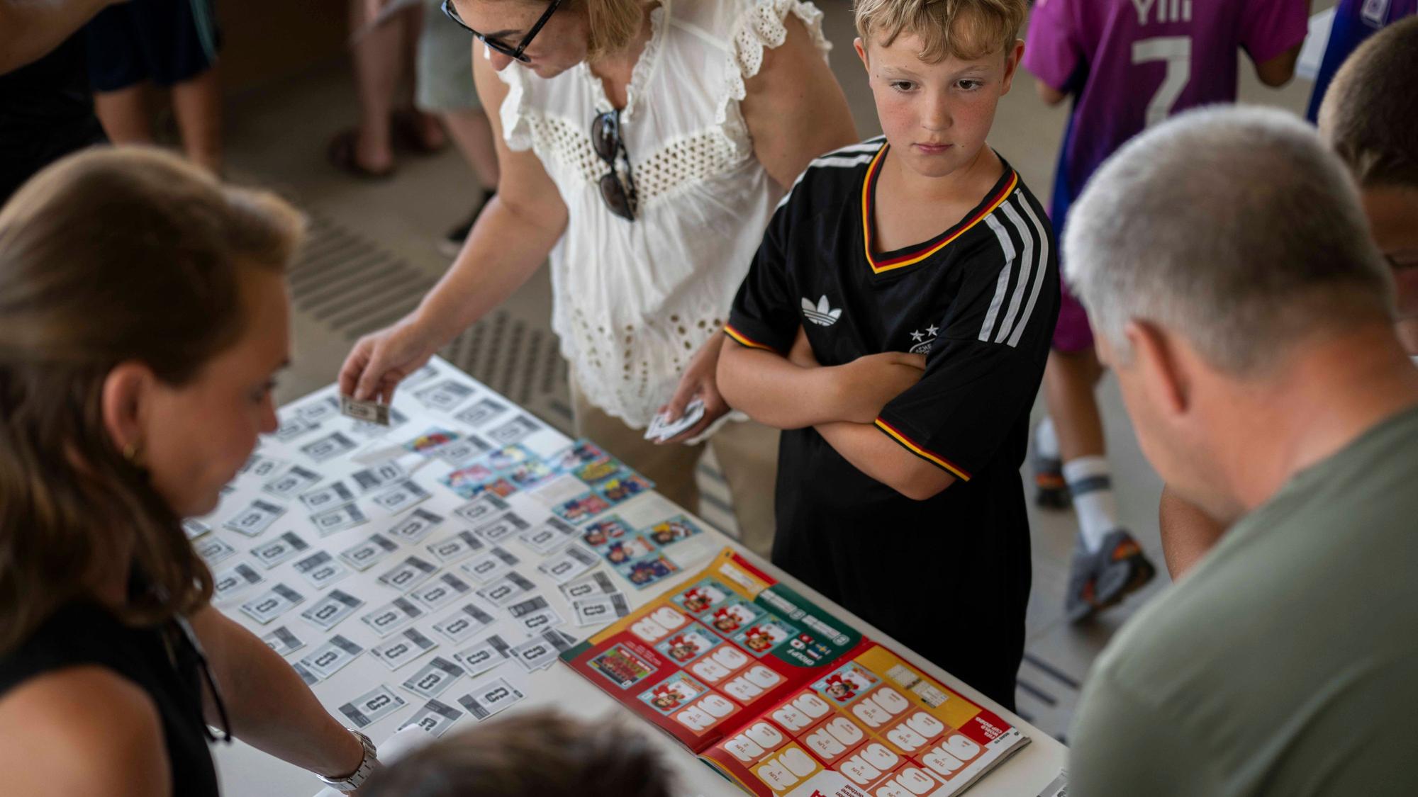 Erwachsene und Kinder beugen sich über Sammelalben.