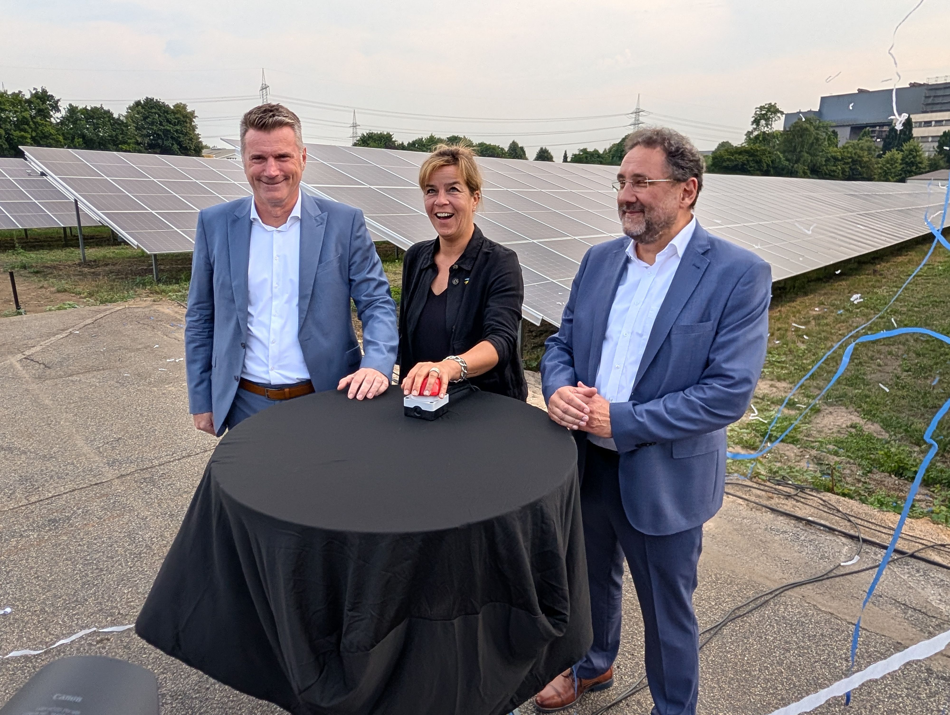 Das Foto zeigt die Geschäftsführer und die Ministerin beim symbolischen Knopfdruck vor einem Teil der Solarmodule.
