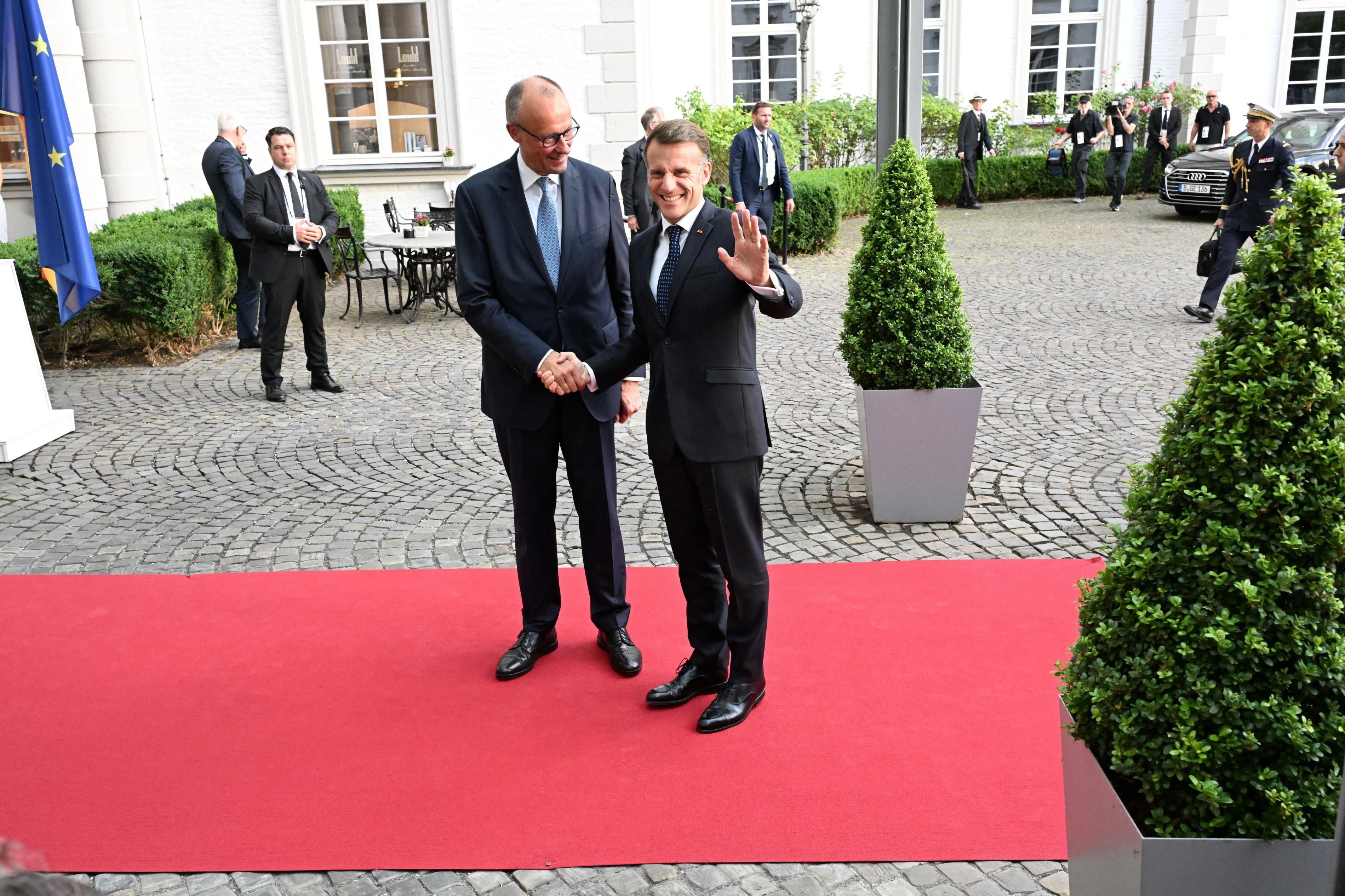 Friedrich Merz Merz und Emmanuel Macron reichen sich die Hand.