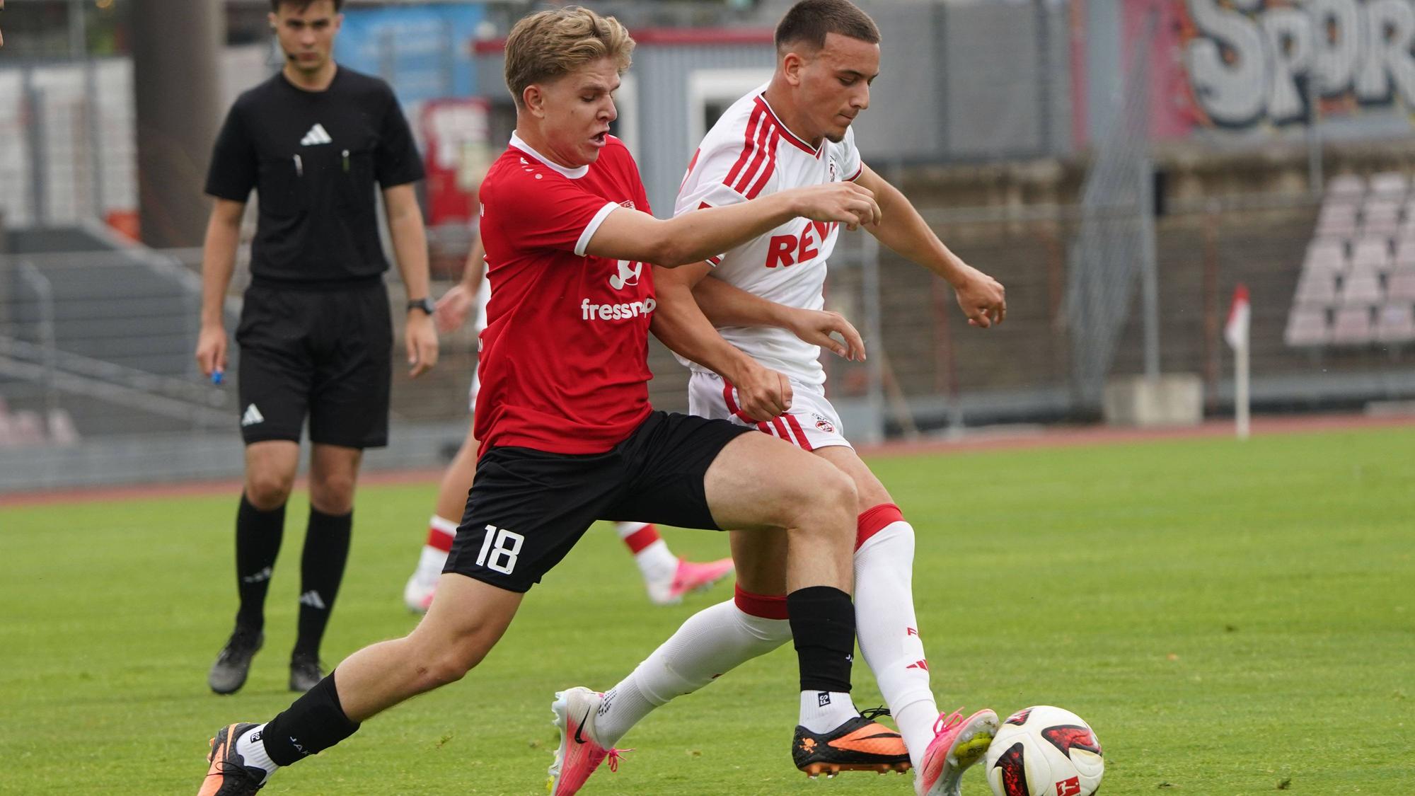 Ein Zweikampf zwischen zwei Fußballern ist zu sehen.
