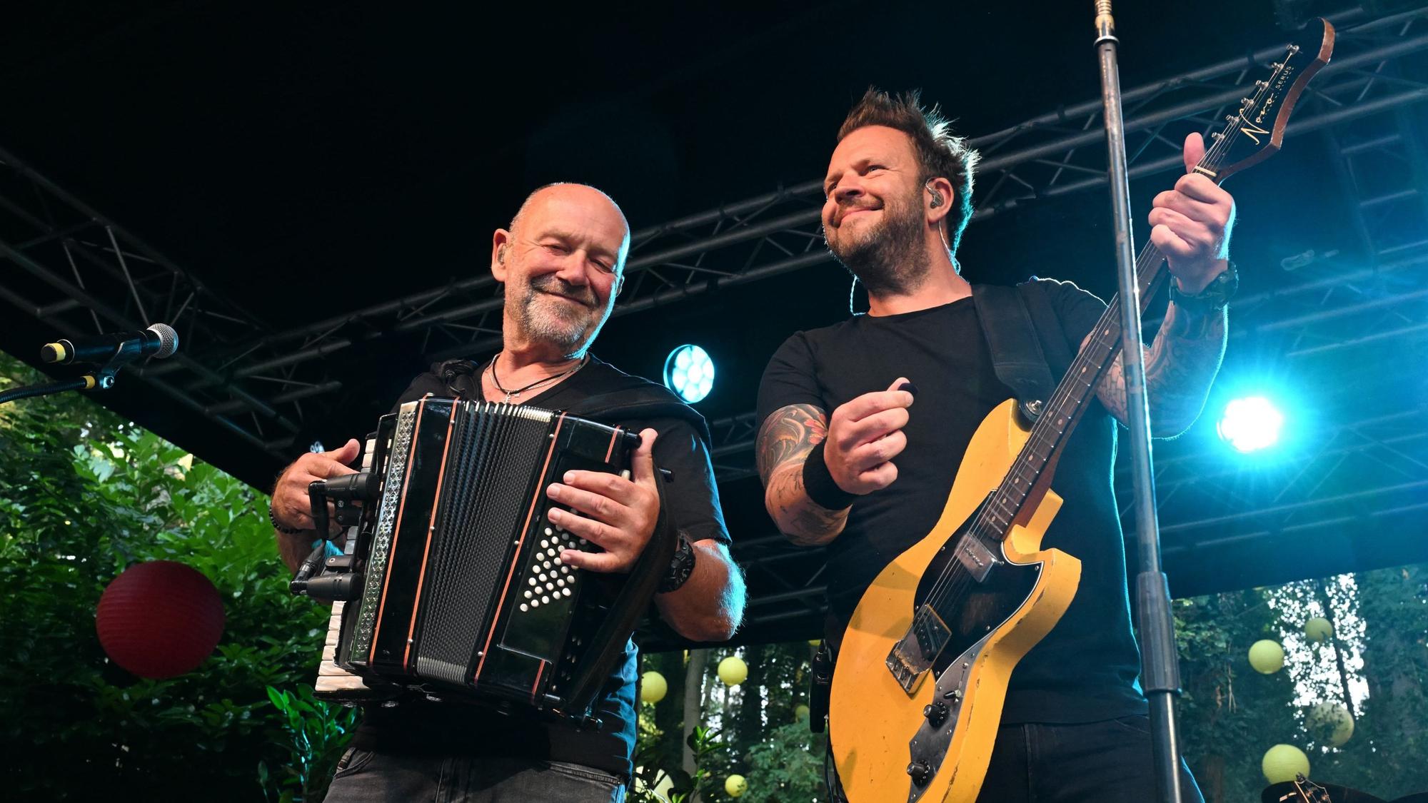 Zwei Männer stehen nebeneinander. Sie spielen Akkordeon und Gitarre.