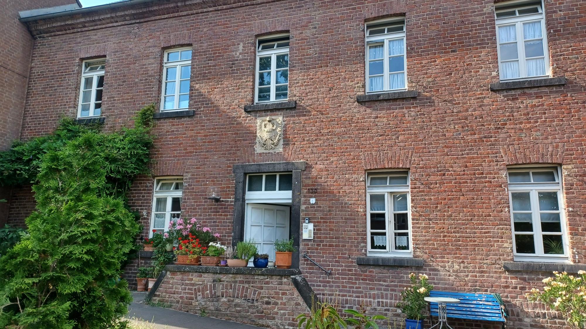 Ein zweigeschossiger Backsteinbau, der zu einem alten Gutshof gehörte, ist zu sehen.
