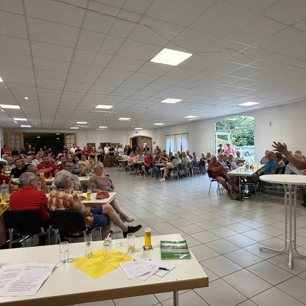 Ein Mann am Stehtisch begrüßt sitzende Gäste.