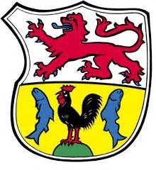 Das Wappen der Gemeinde Much zeigt oben einen Bergischen Löwen und unten einen Hahn, der von Fischen flankiert ist.