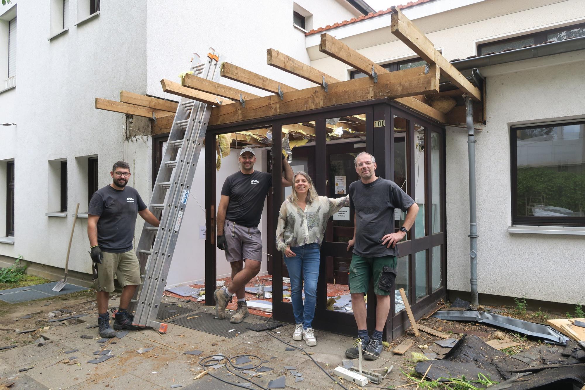 Drei Männer und eine Frau stehen vor einem Gebäude, das umgebaut wird.