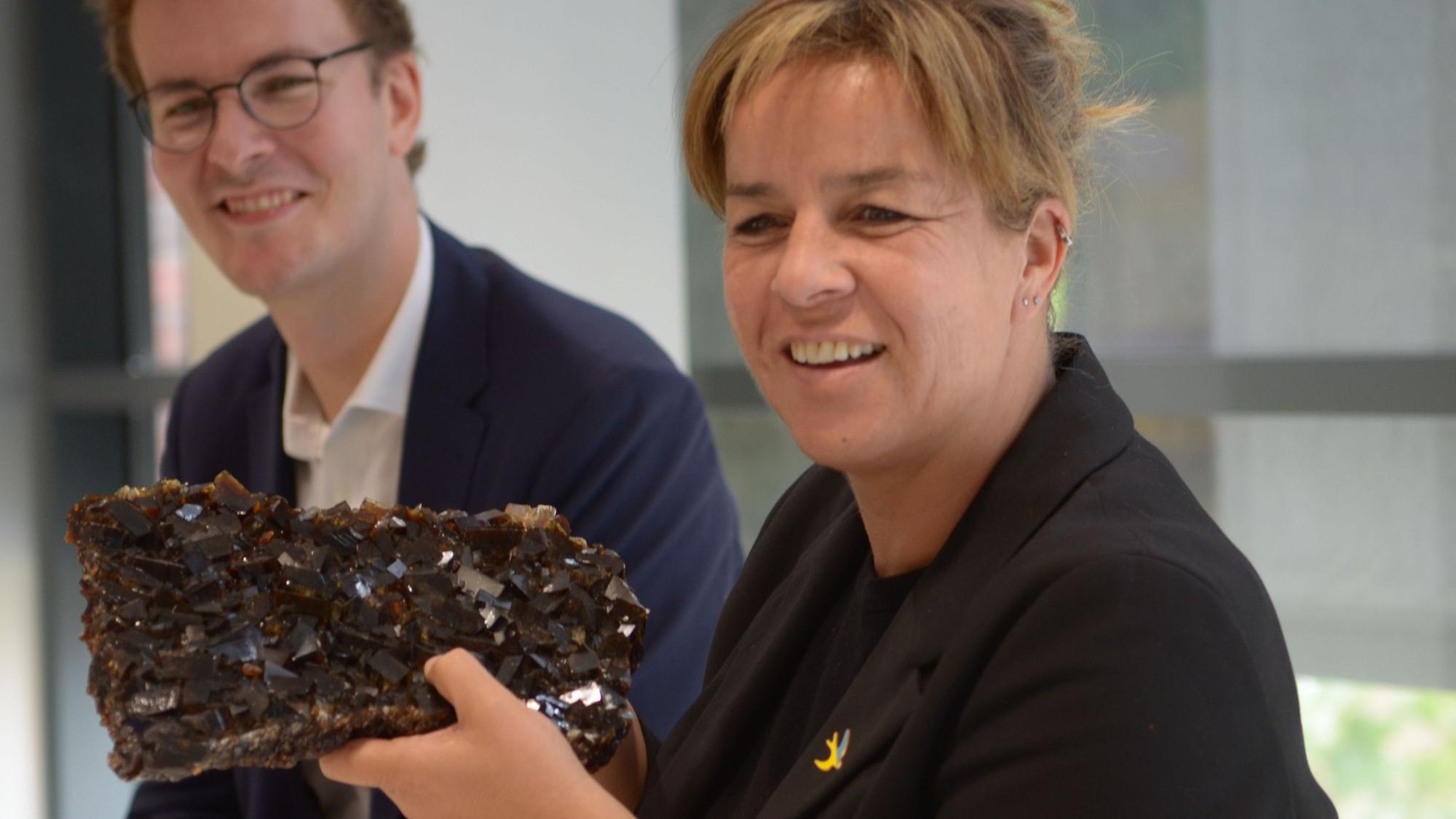 NRW-Wirtschaftsministerin Mona Neubaur hält beim Besuch der Firma Pfeifer & Langen in Euskirchen ein großes Stück Kandiszucker in den Händen.