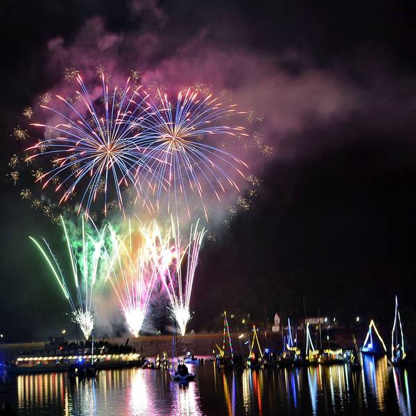 Feuerwerk explodiert am Nachtimmel und spiegelt sich im Wasser.