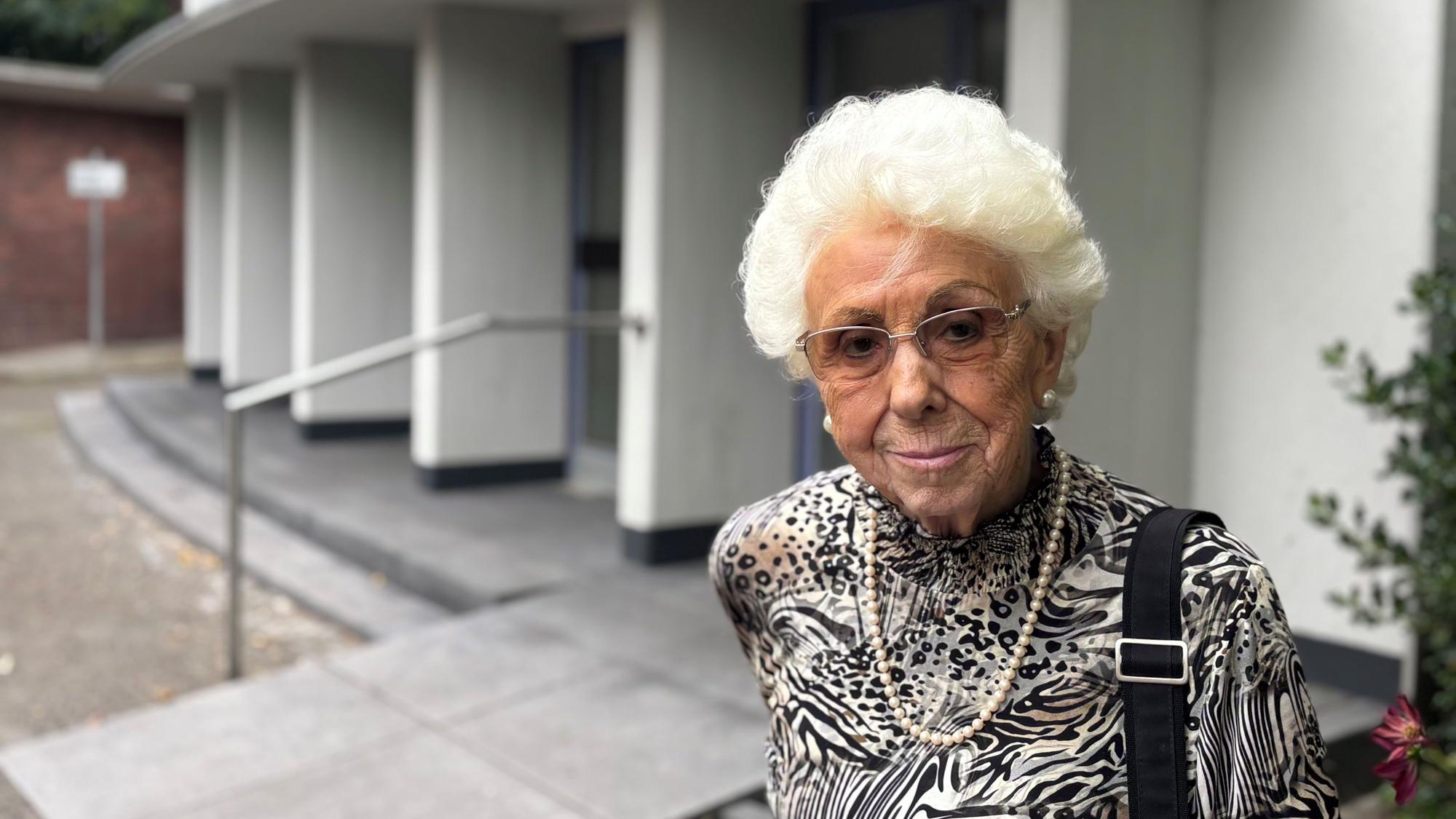 Auf dem Foto ist eine ältere Dame vor der Trauerhalle in Frechen zu sehen.