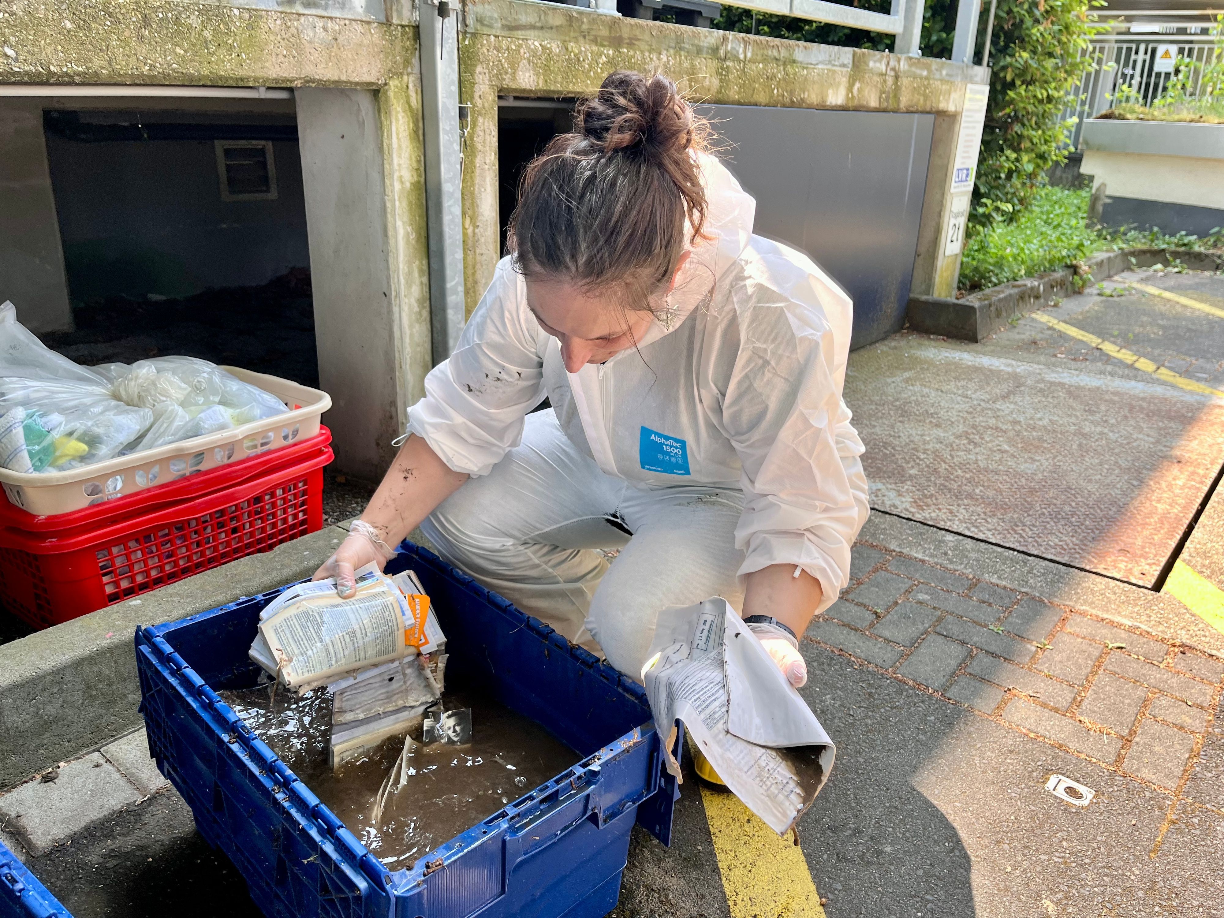 Eine Frau nimmt durchnässtes Papier aus einem mit Wasser befüllten Behälter.