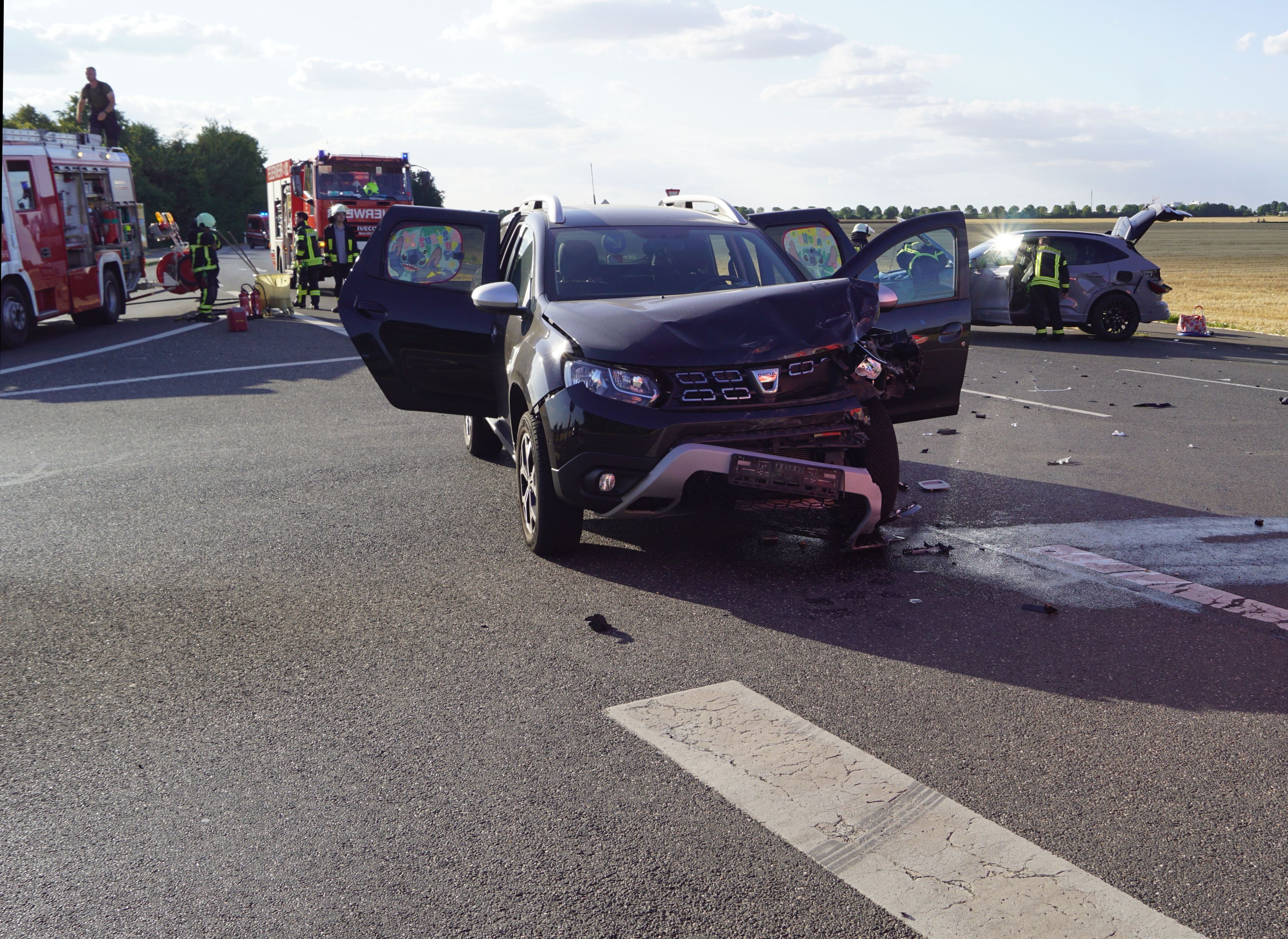 Zwei beschädigte Autos und zwei Feuerwehrfahrzeuge stehen nach einem Unfall auf einer Straße in Zülpich.