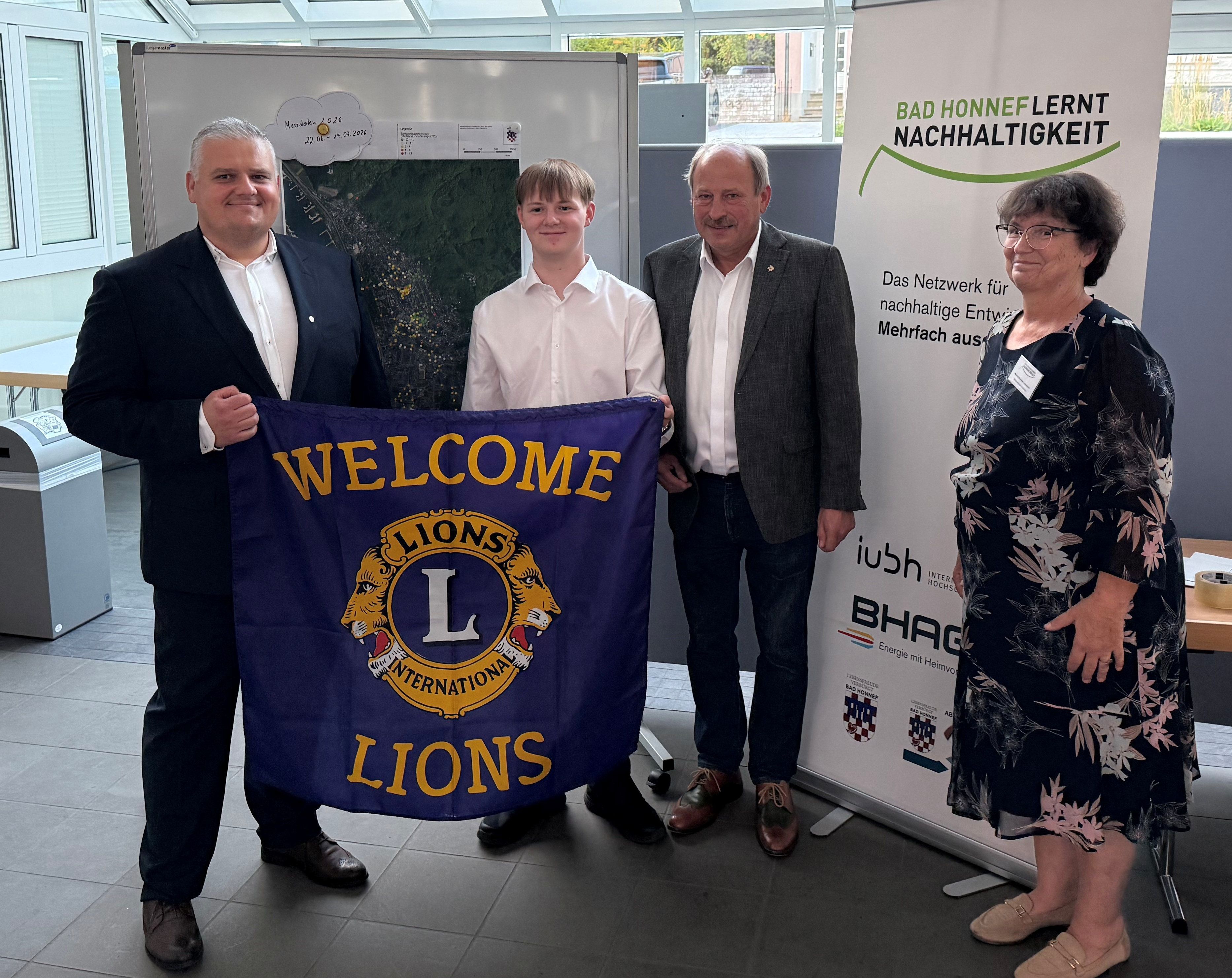 Vier Personen mit einem Banner mit der Aufschrift „Welcome Lions“.