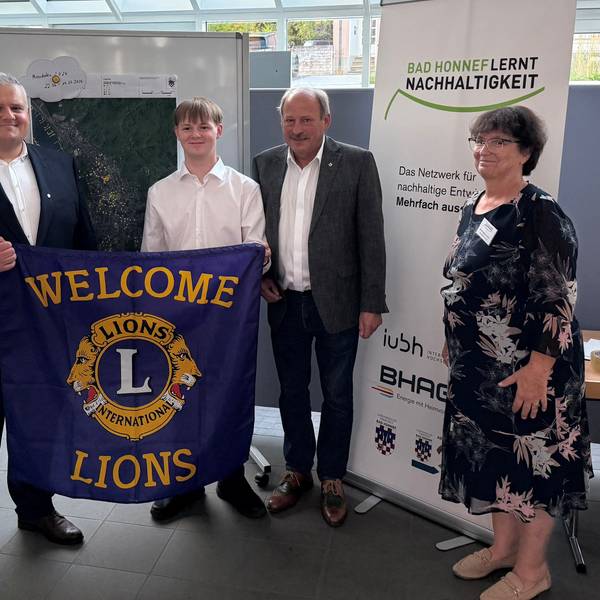 Vier Personen mit einem Banner mit der Aufschrift „Welcome Lions“.