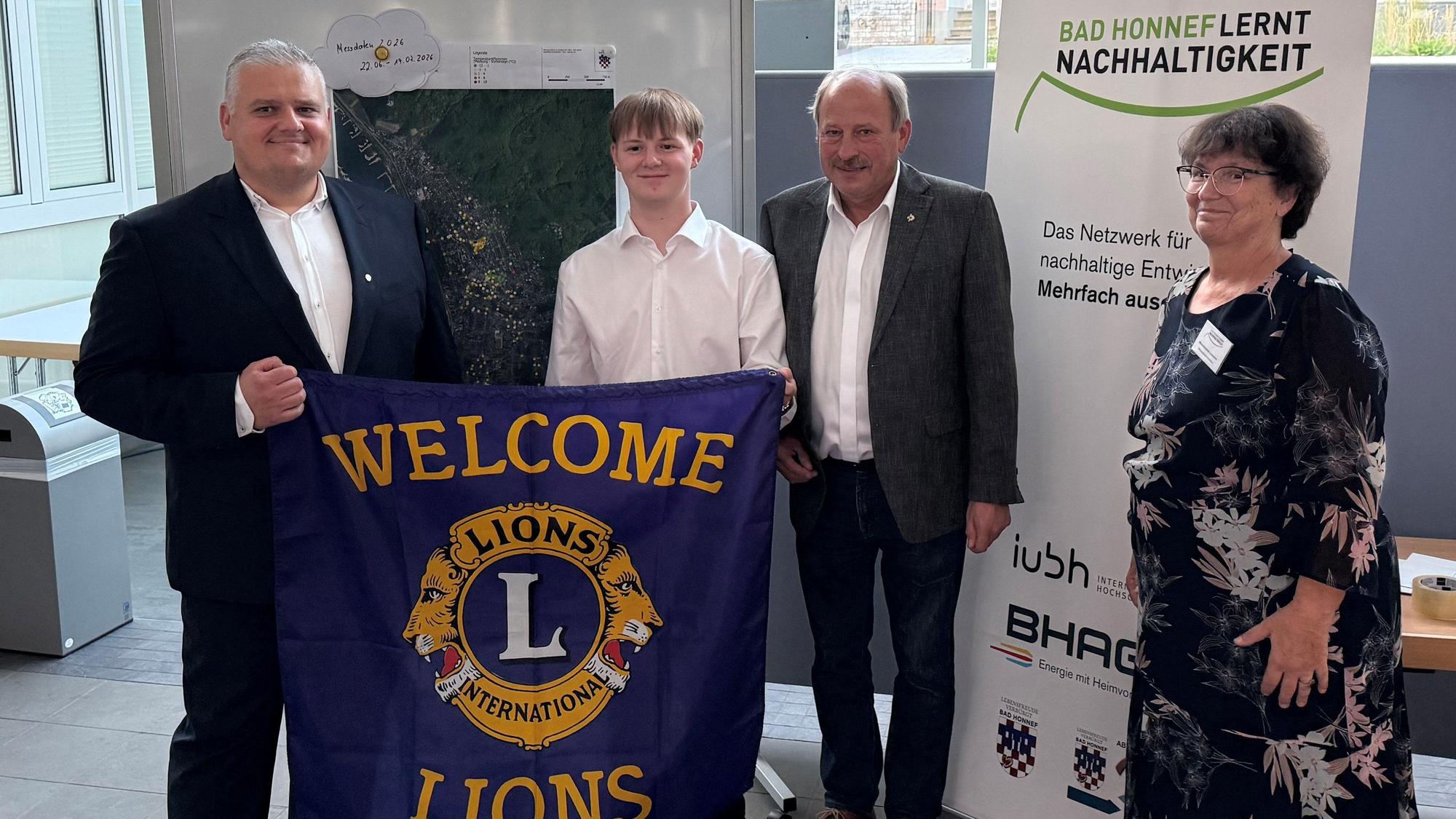 Vier Personen mit einem Banner mit der Aufschrift „Welcome Lions“.