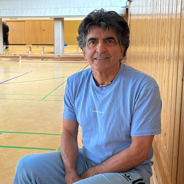 Ein Mann sitzt in einer Sporthalle.