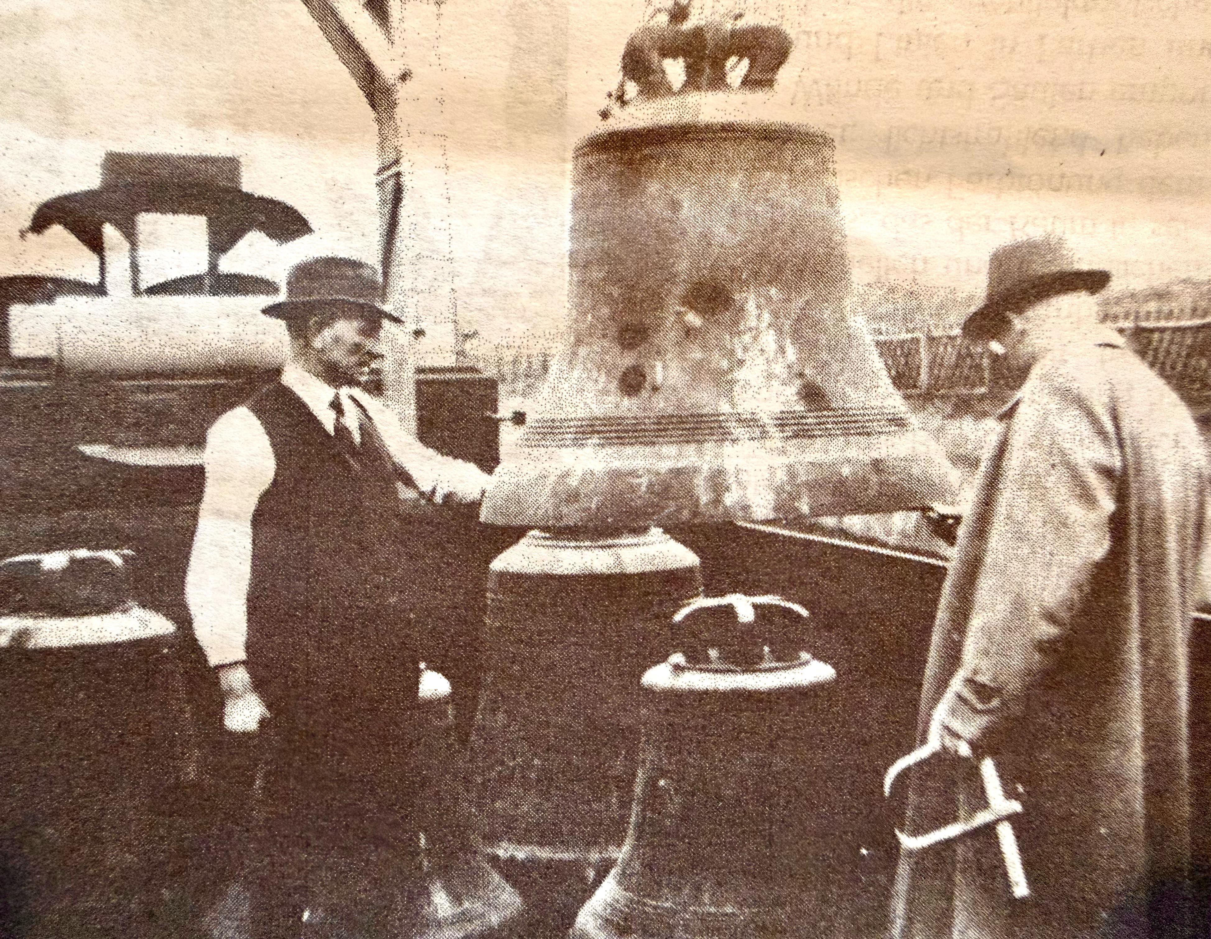 Das historische Bild zeigt zwei Männer, die eine Kirchenglocke verladen.