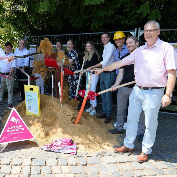 Die Vertreter der Kommunen und der beteiligten Firmen haben sich im Halbkreis um einen Sandhügel gruppiert, um mit Schaufeln den ersten Spatenstich durchzuführen.