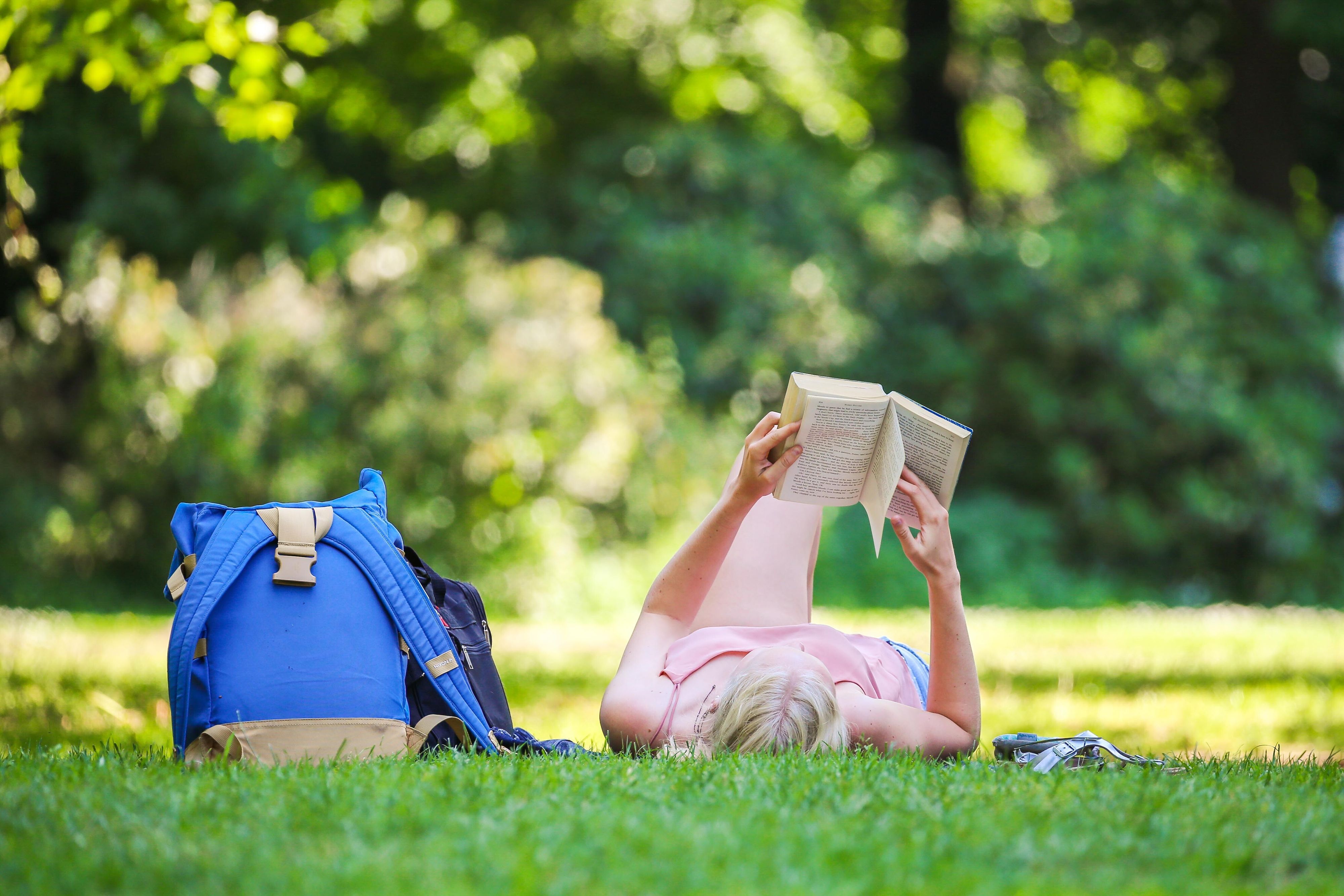 Eine Frau liest ein Buch in einem Park.