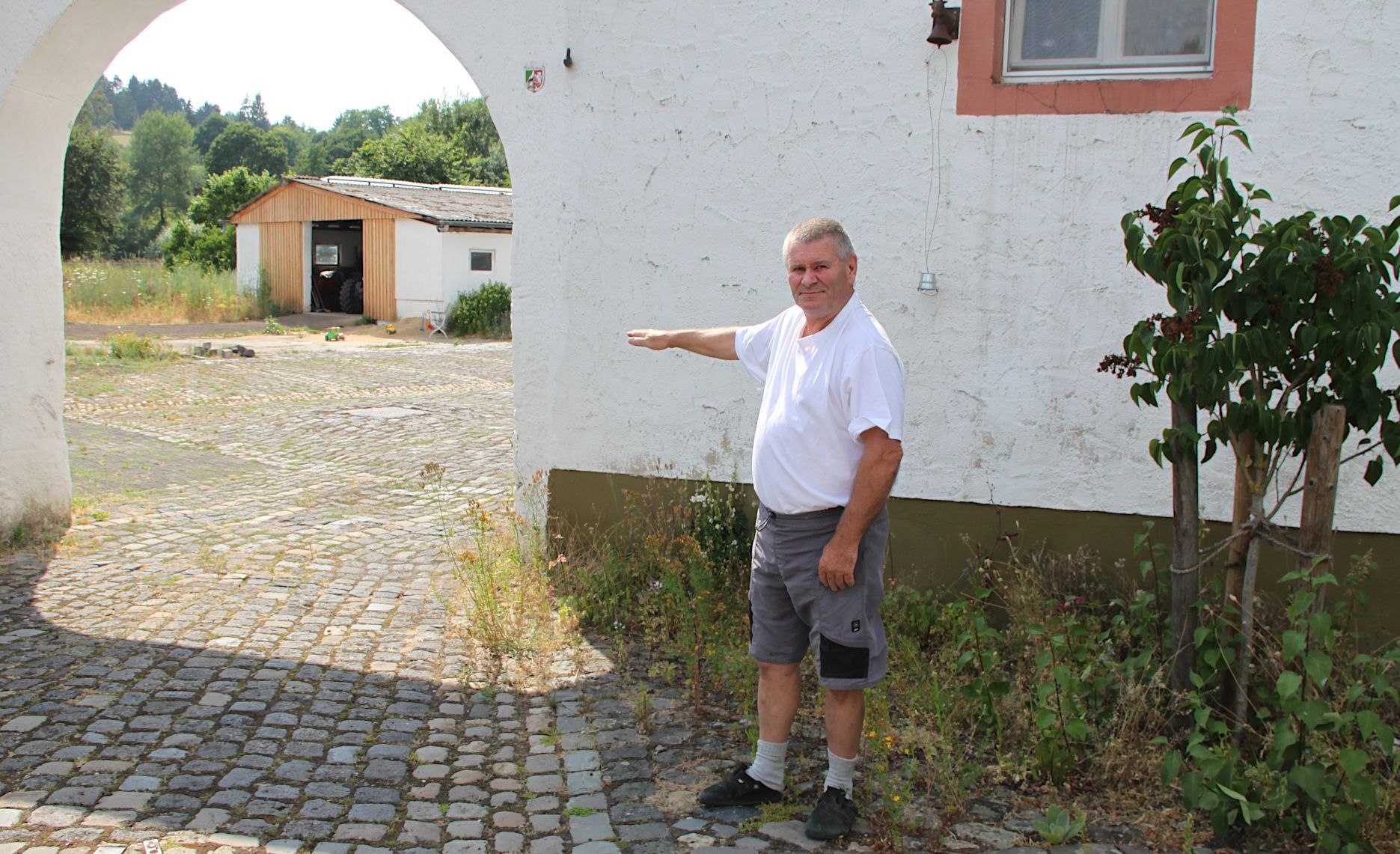 Josef Reuter zeigt an der Einfahrt zu seinem Hof, wie hoch das Wasser 2021 dort stand.
