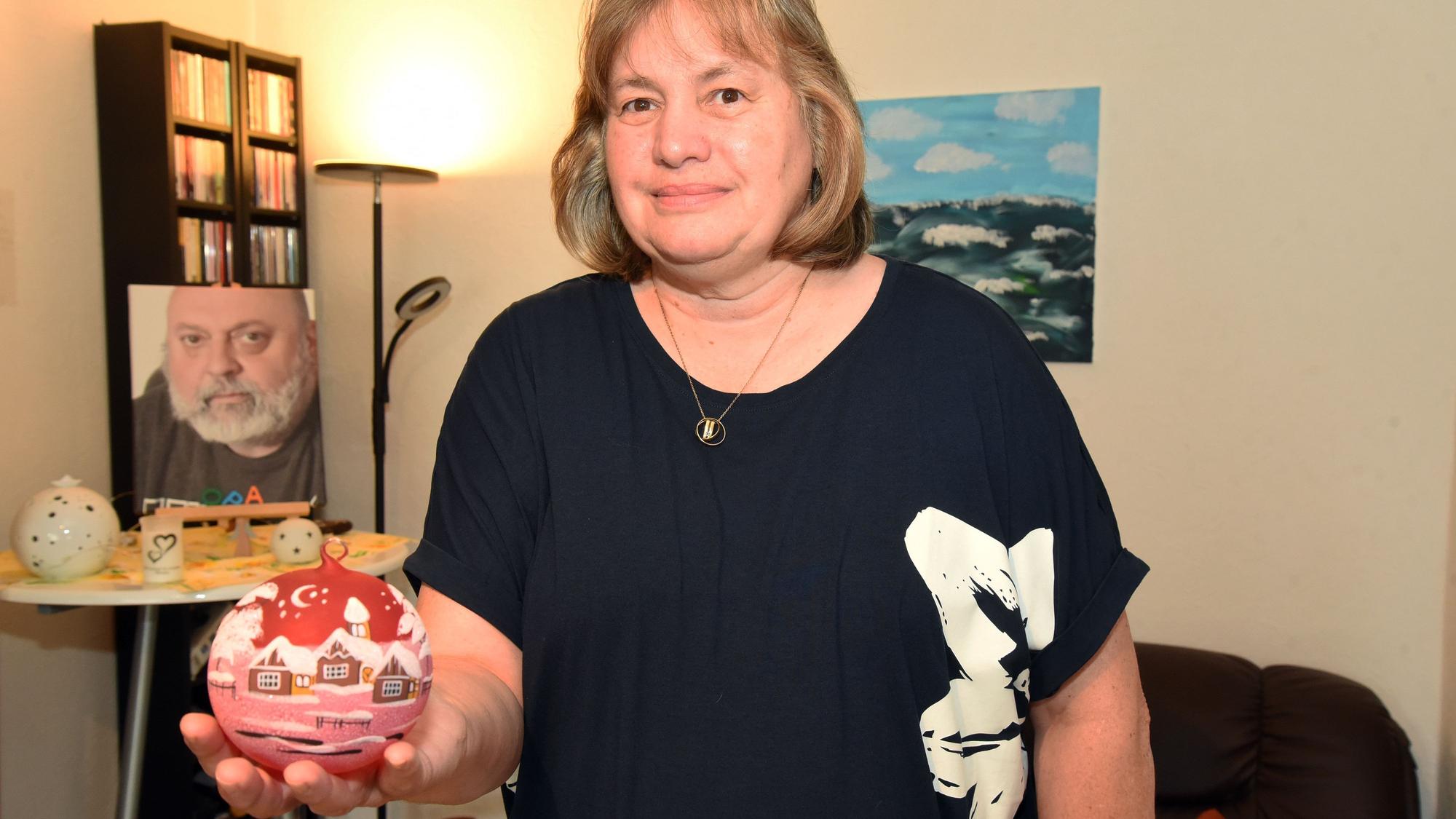 Eine Frau zeigt eine Christbaumkugel.