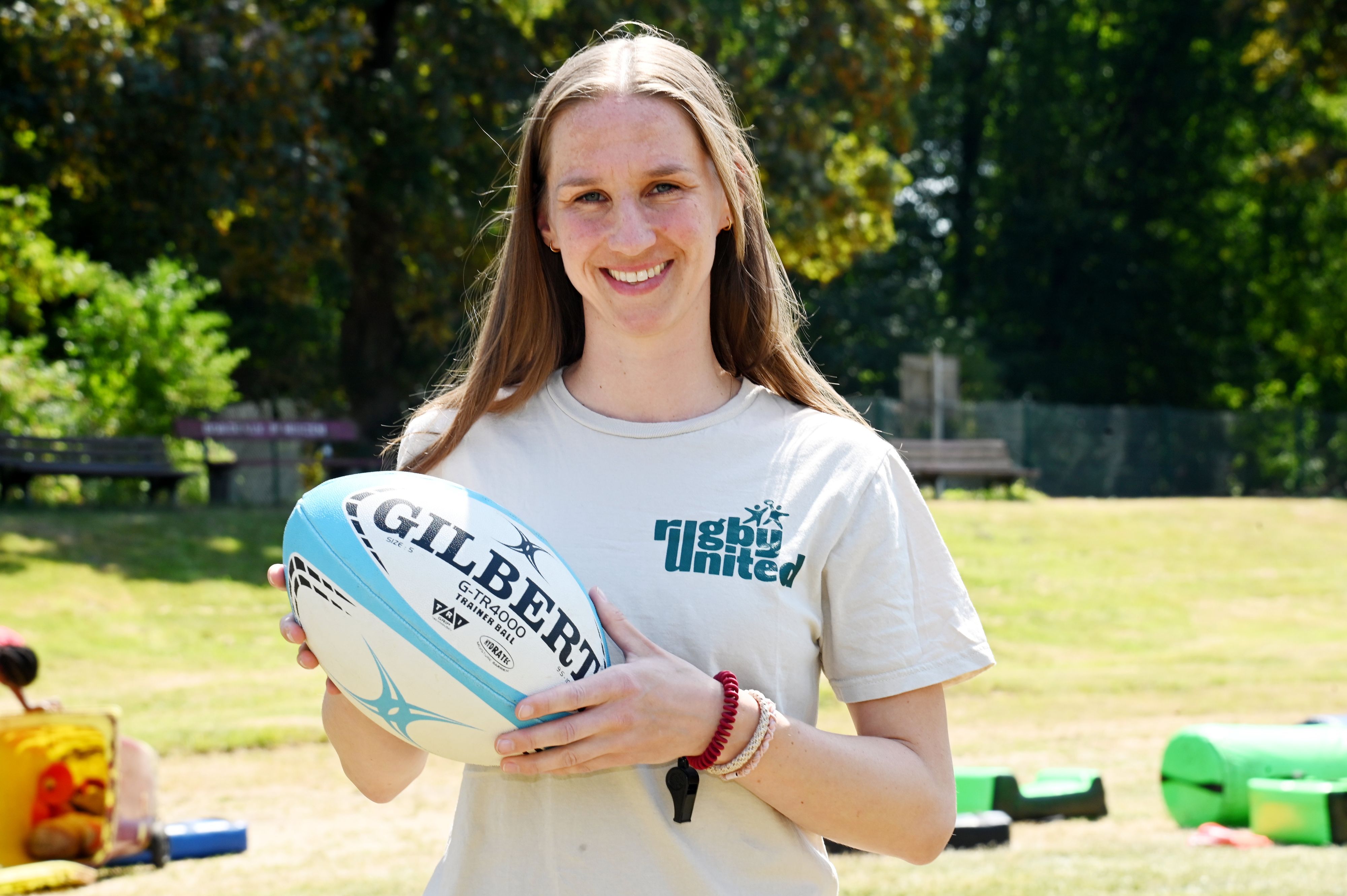 Eine Frau mit Rugbyball in den Händen und einem Shirt, auf dem „Rugby United“ steht.