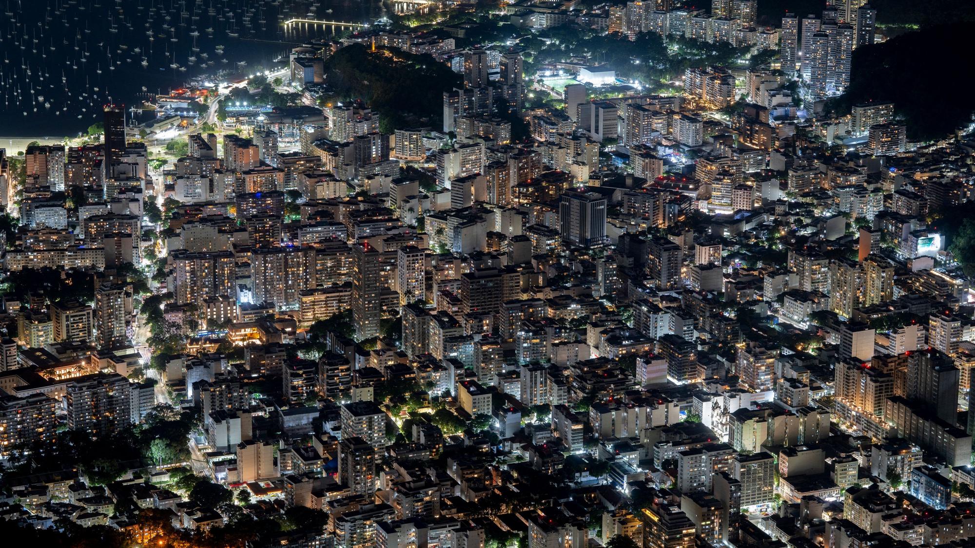 Blick von oben auf die nächtlich erleuchteten Gebäude an der Guanabara-Bucht, aufgenommen vom Berg Corcovado im Tijuca-Nationalpark in Rio de Janeiro, Brasilien.