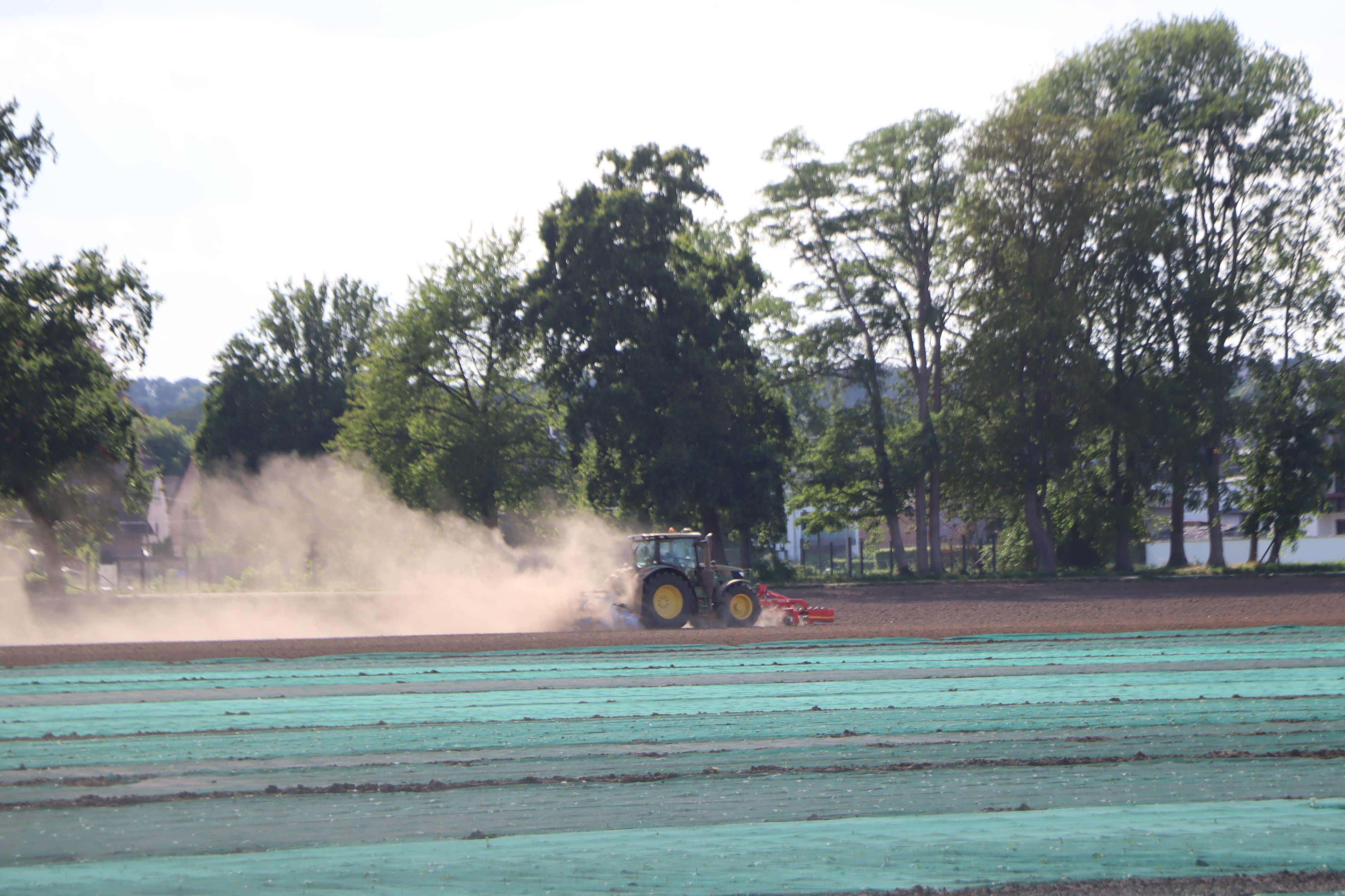 Ein Traktor bewirtschaftet ein Feld und wirbelt Staub auf.