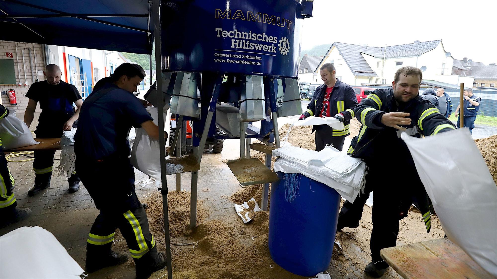 THW-Mitglieder füllen mit Hilfe einer Maschine Sandsäcke.