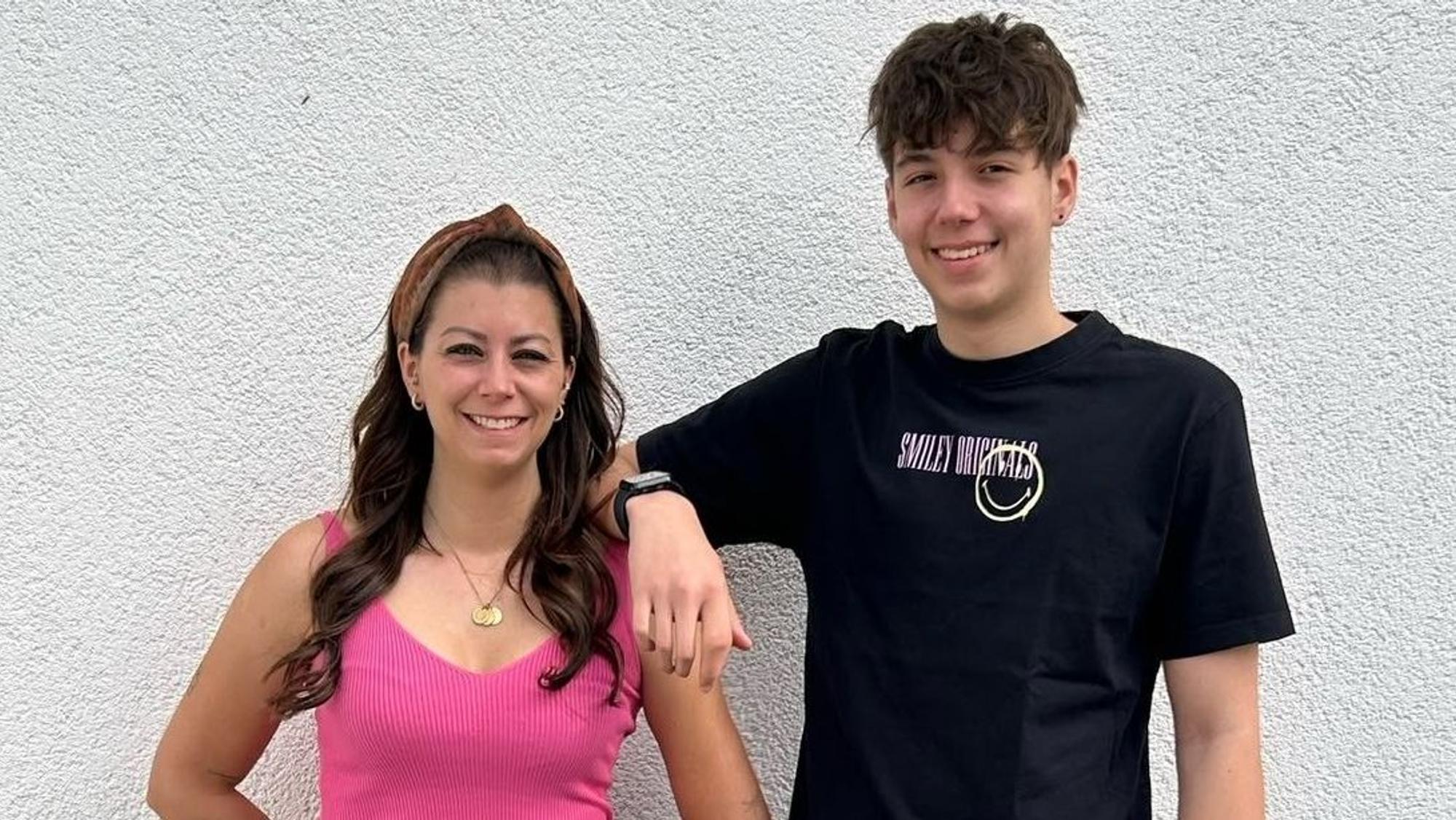 Mutter und Sohn stehen nebeneinander. Er hat einen Arm auf ihre Schulter gelegt.