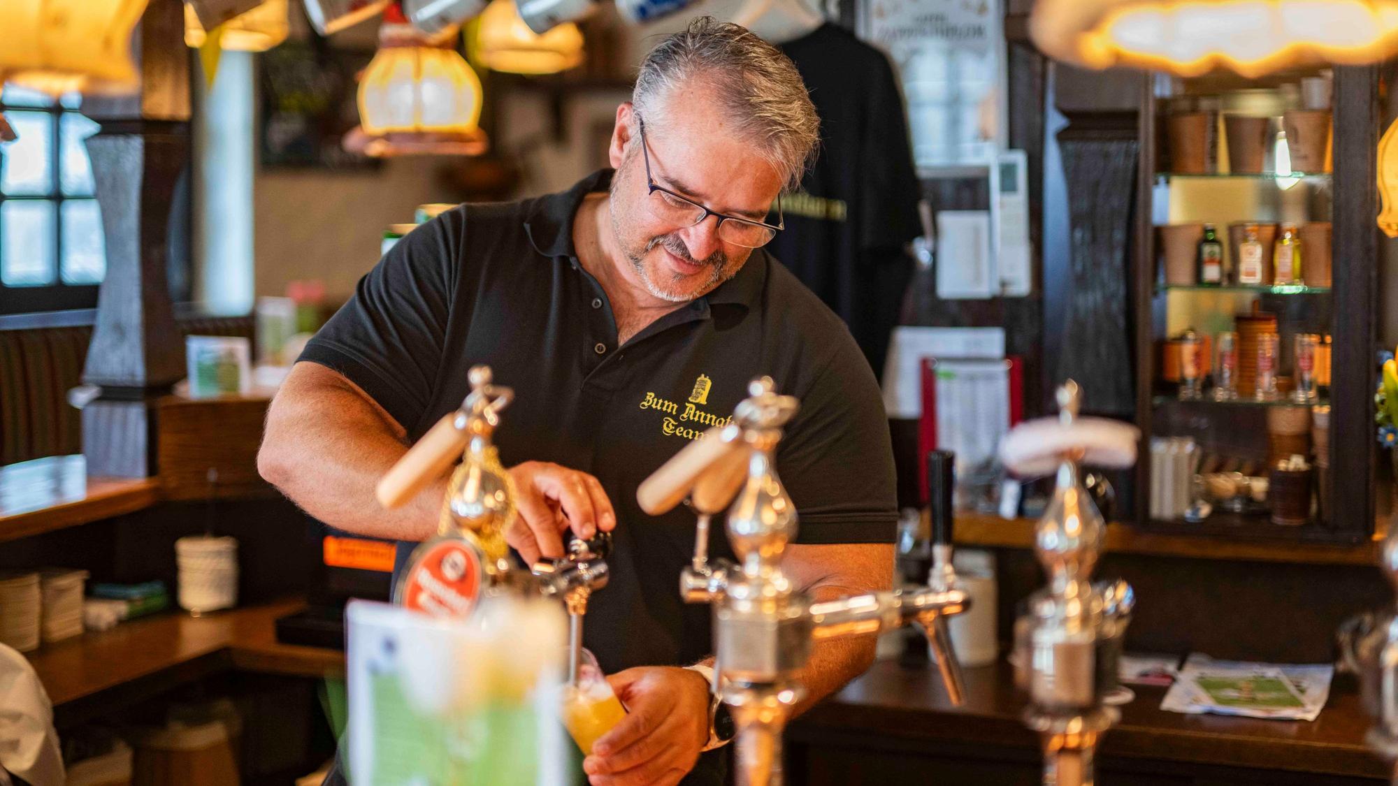 Das Bier zeigt Markus Tews hinter der Theke der Kneipe am Annaturmplatz.