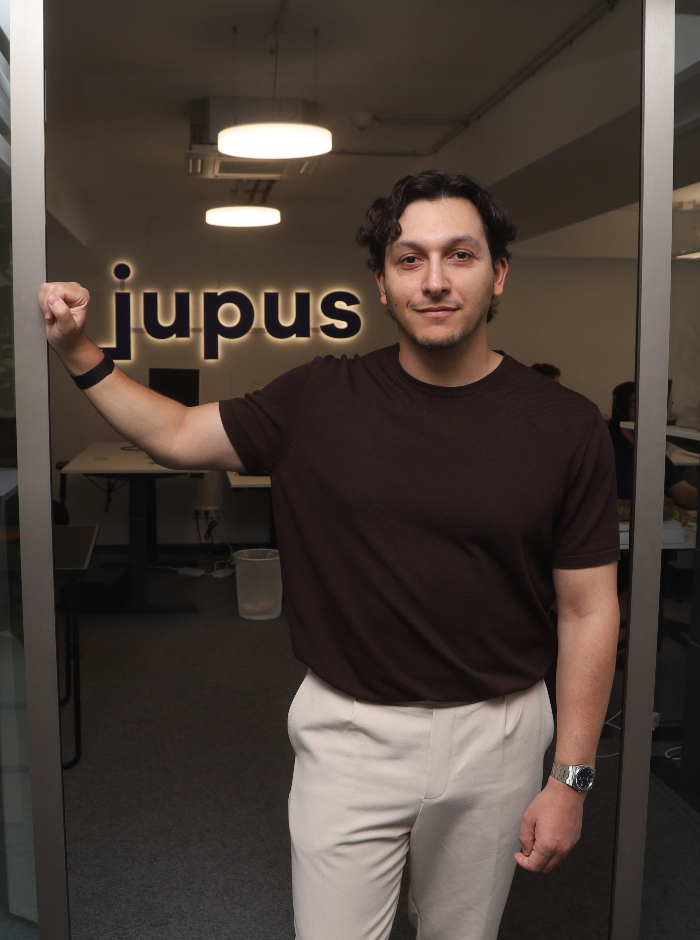 René Fergen steht im Büro vor einem Schriftzug des Unternehmens Jupus