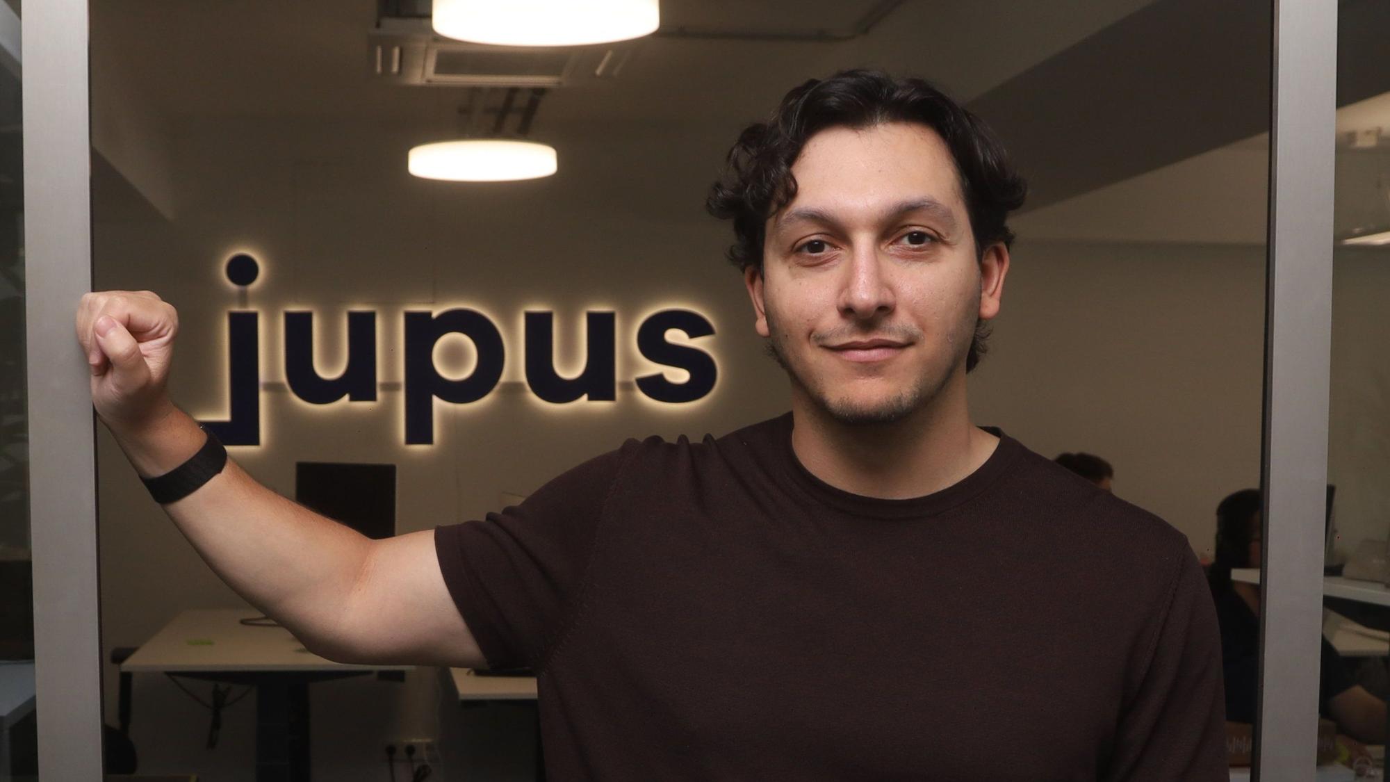 René Fergen steht im Büro vor einem Schriftzug des Unternehmens Jupus