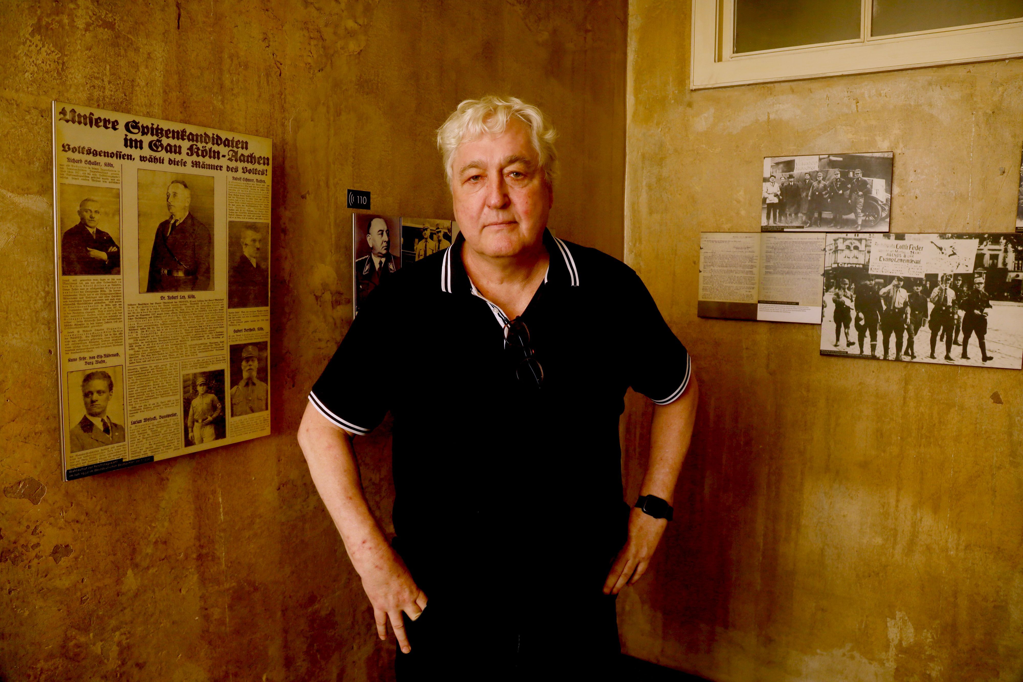Der Journalist Axel Spilcker zu Besuch im NS-Dokumentationszentrum in Köln. An der Wand der Ausstellung hängt ein Artikel aus der NS-Zeit mit einem Foto seines Großvaters Robert Ley.