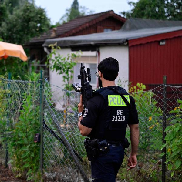 Ein Polizeibeamter mit einer automatischen Waffe geht am 26. Juli 2026 in einer Kleingartenanlage im Berliner Stadtteil Spandau durch einen Gartenbereich in der Nähe der Stelle, an der der Hauptverdächtige erschossen wurde.