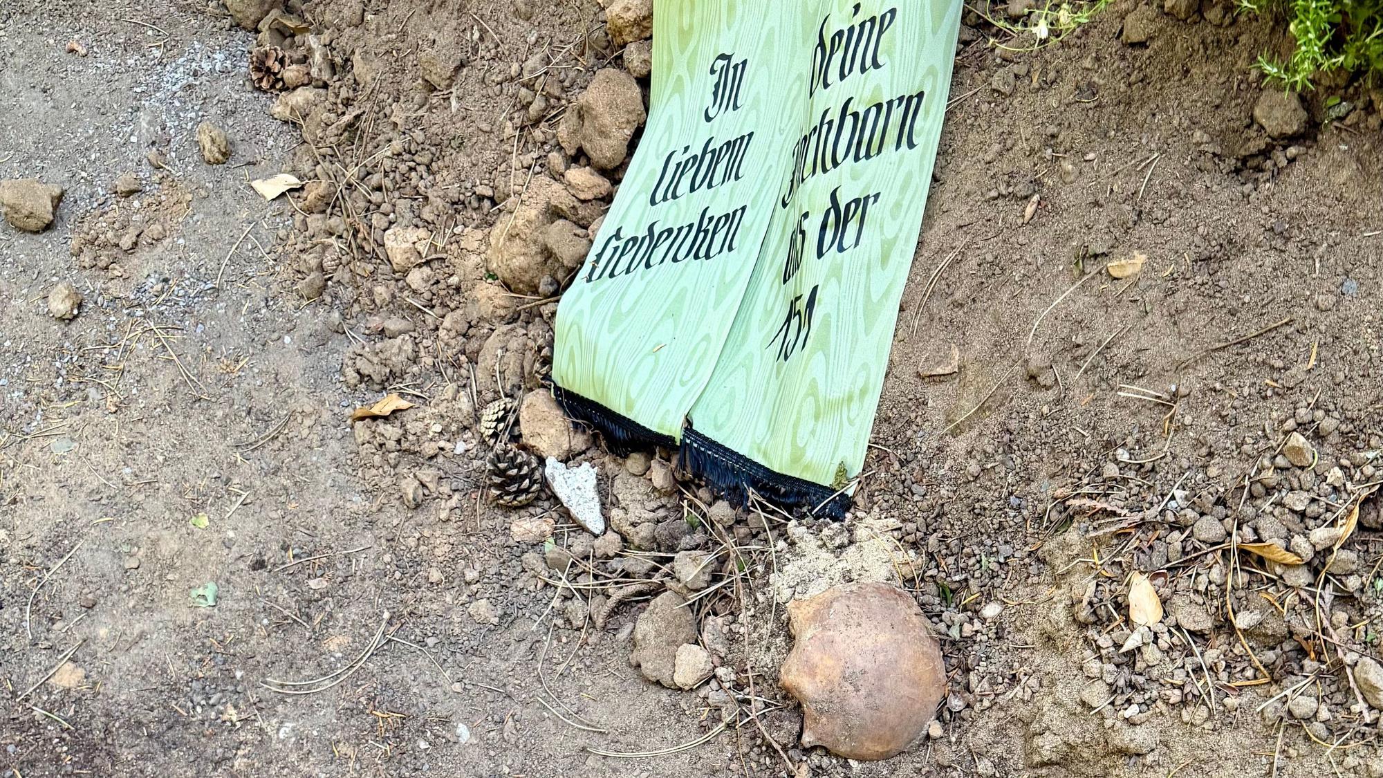 Neben einem Grab liegt ein Teil von einem menschlichen Schädel.