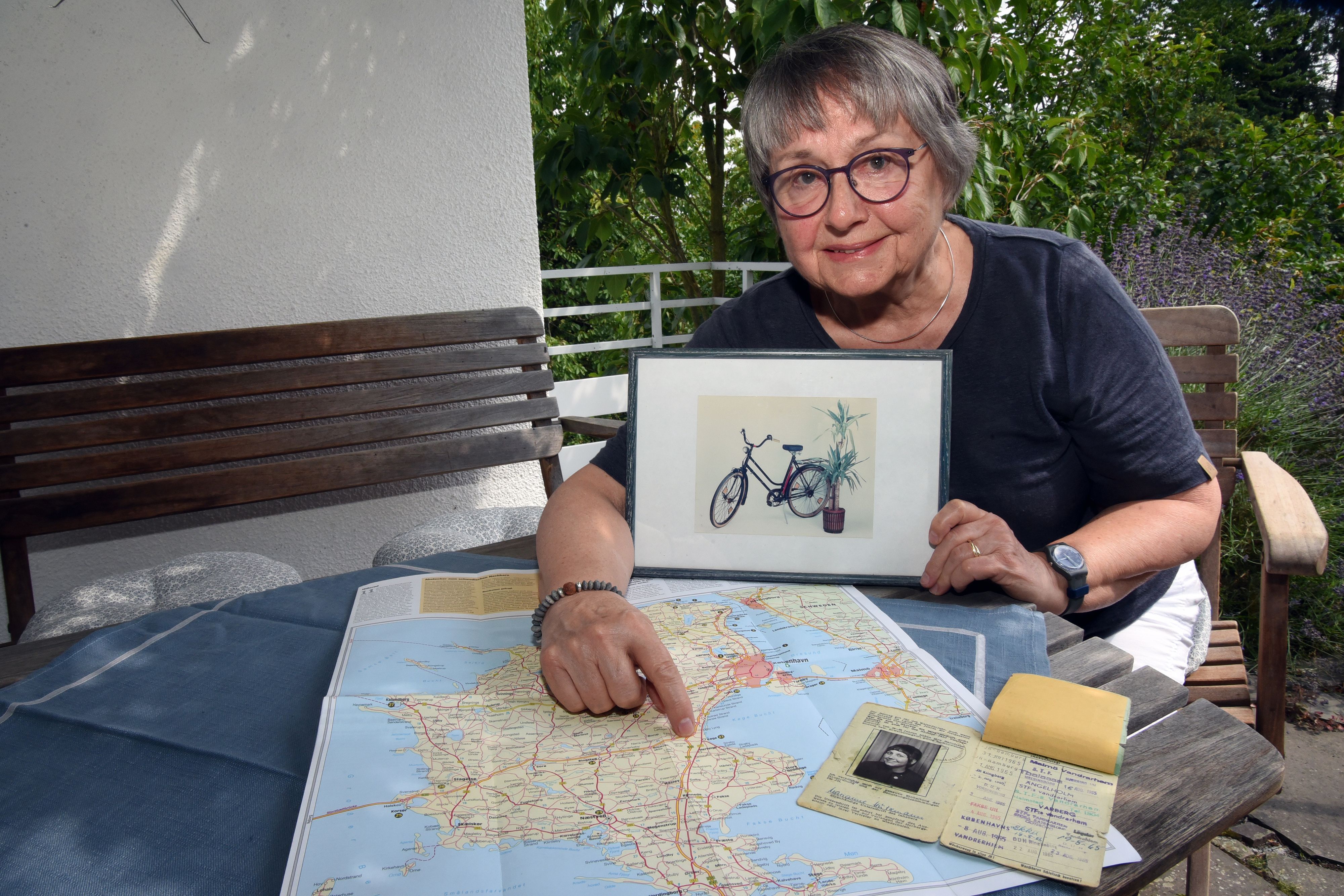 Eine Frau zeigt das Foto eines Fahrrads und eine Landkarte.