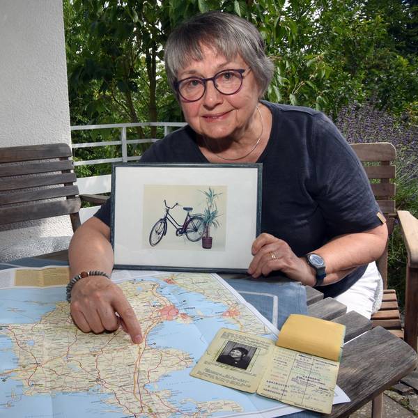 Eine Frau zeigt das Foto eines Fahrrads und eine Landkarte.