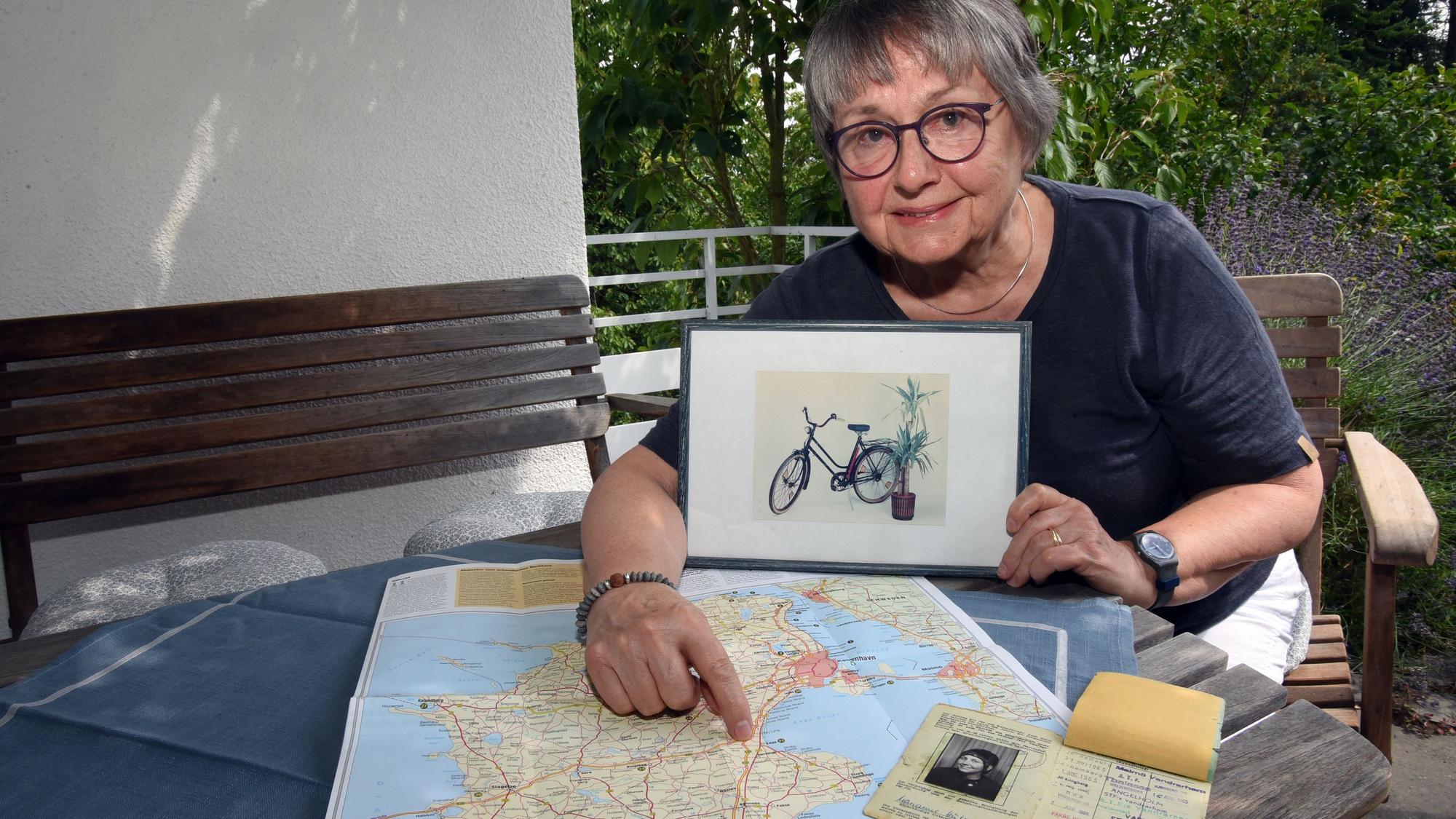 Eine Frau zeigt das Foto eines Fahrrads und eine Landkarte.