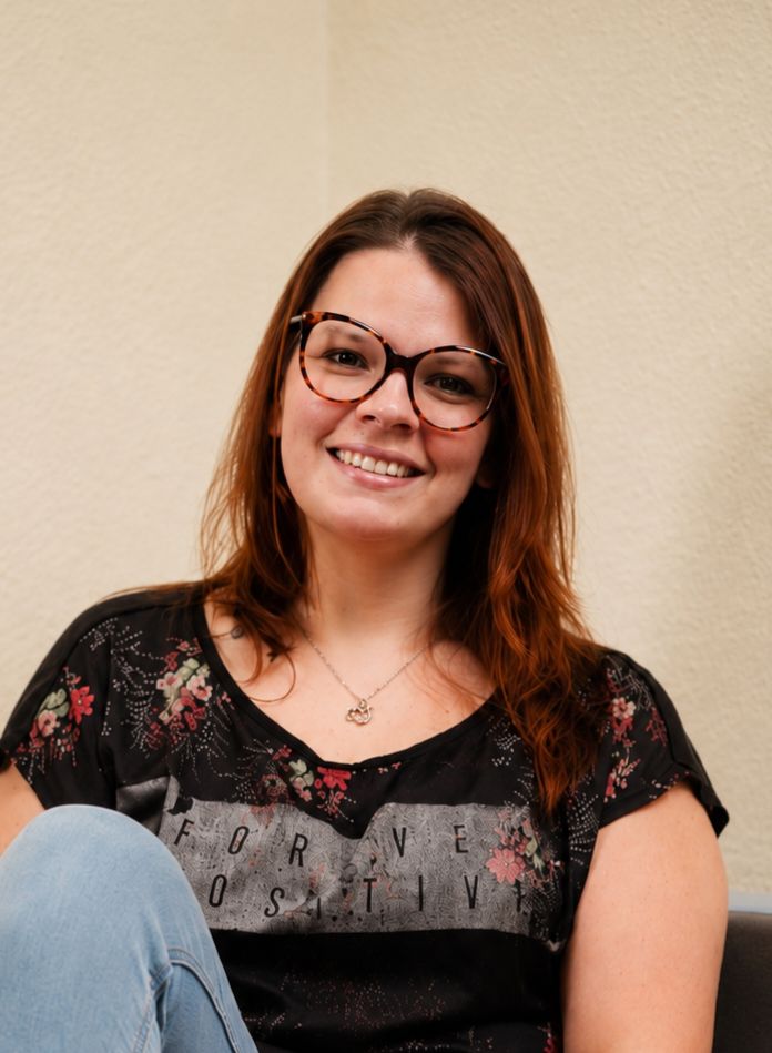 Das Bild zeigt Sandra Cornely. Sie lächelt, trägt eine Brille und hat lange, braune Haare.