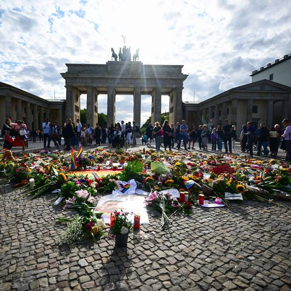 Menschen stehen an Beileidsbekundungen, Blumen, Flaggen und Kerzen, die vor dem Brandenburger Tor abgelegt wurden. Im Tiergarten war am Rande des Christopher Street Day ein Mann mit einem Fahrzeug in eine Menschenmenge gefahren.